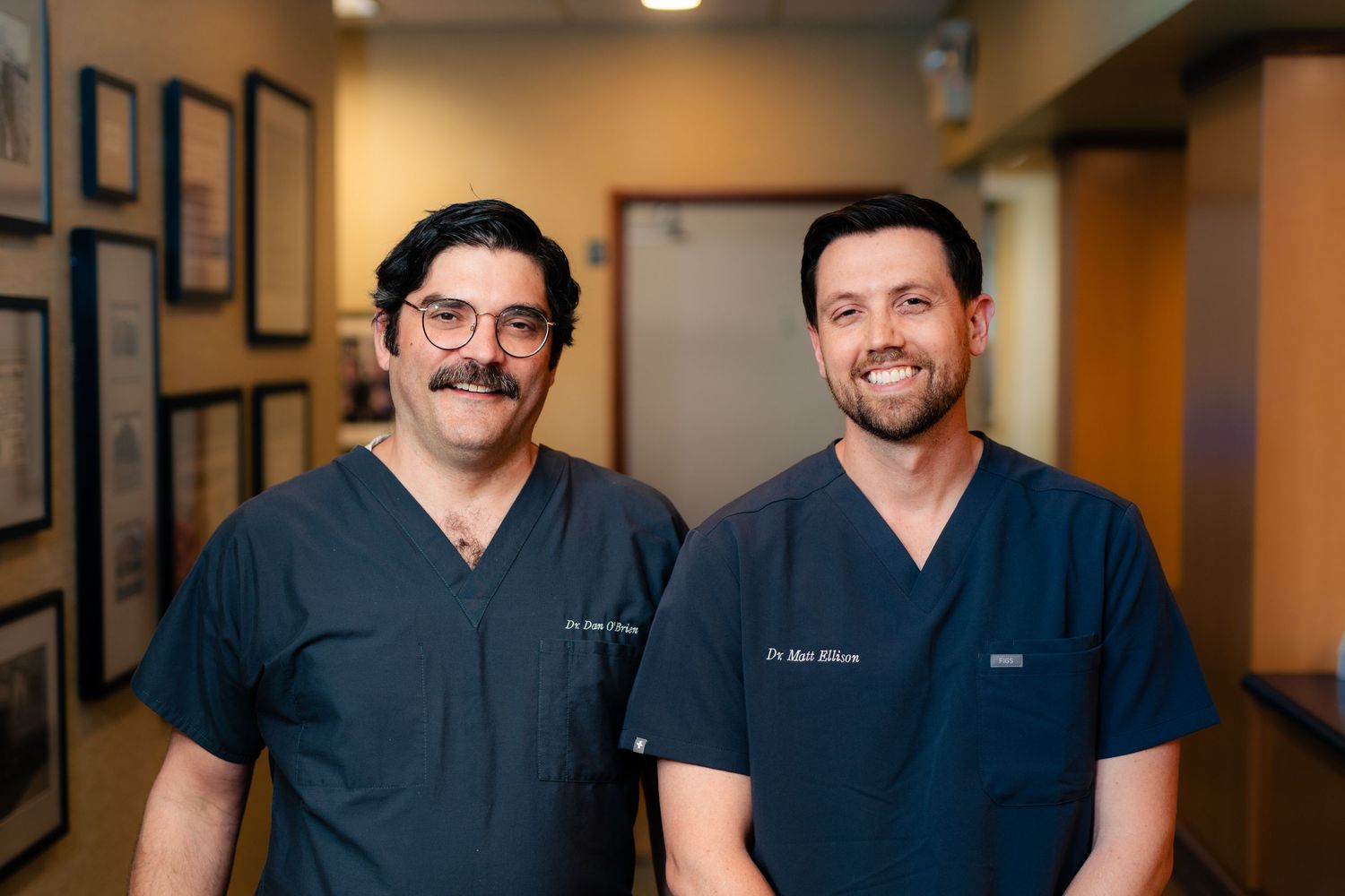 Grand rapids dentists in navy blue scrubs stand together in a hallway for a headshot session