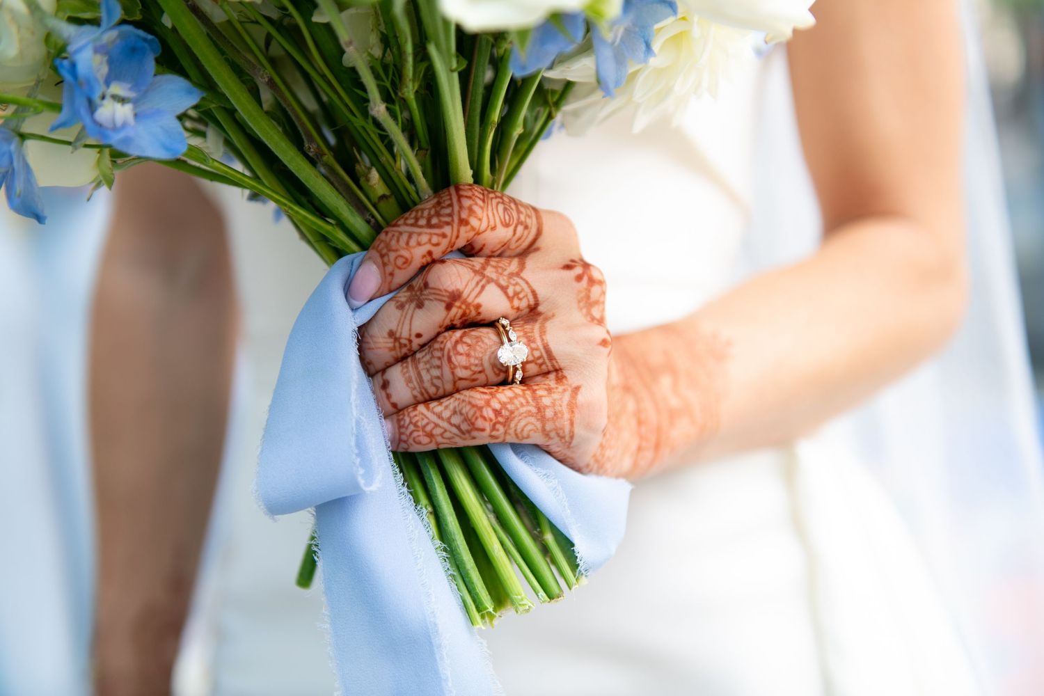A row of bridesmaids in light blue dresses holding white flower bouquets at a wedding ceremony.
