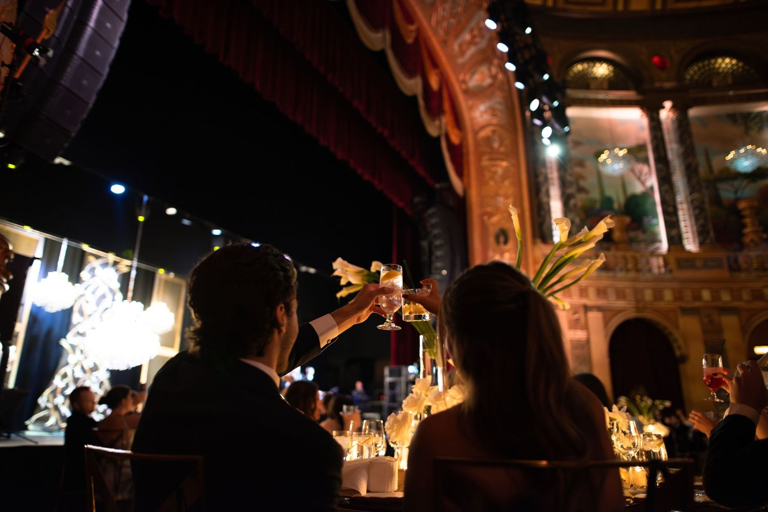 Illuminated ornate theater interior with dark wood panels and glowing vintage light fixtures casting warm ambient light.