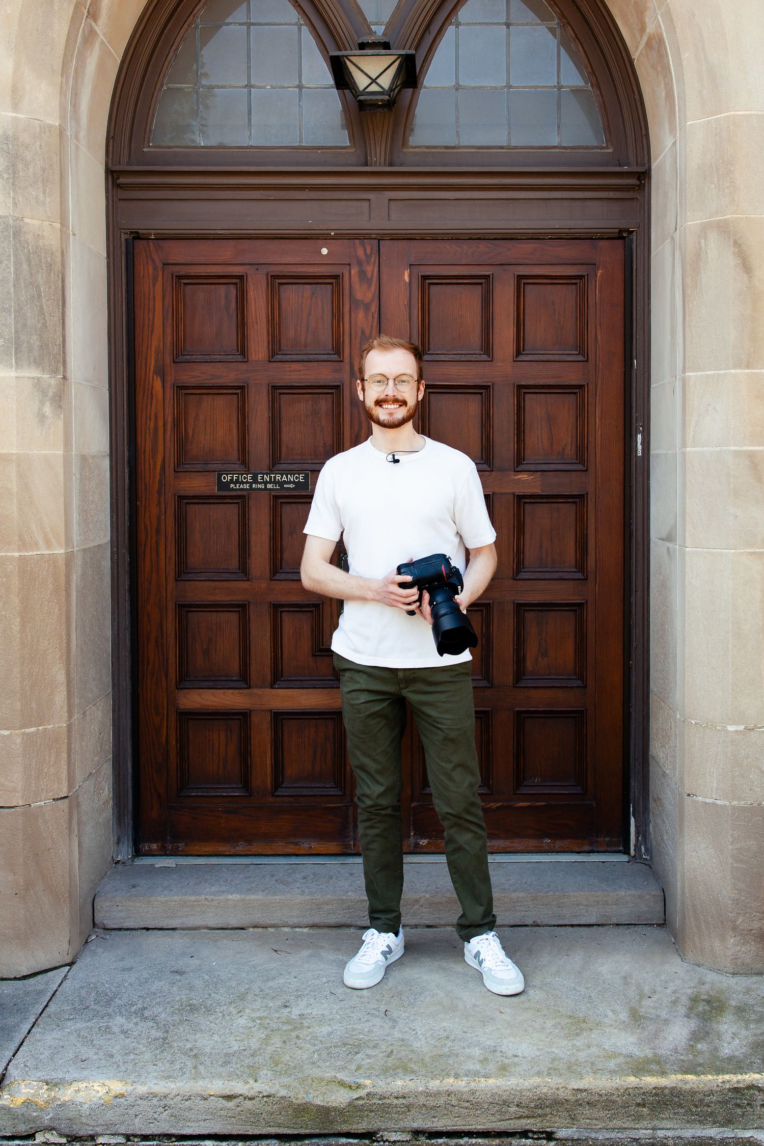 west michigan photographer micah hill poses for camera in front of wooden door