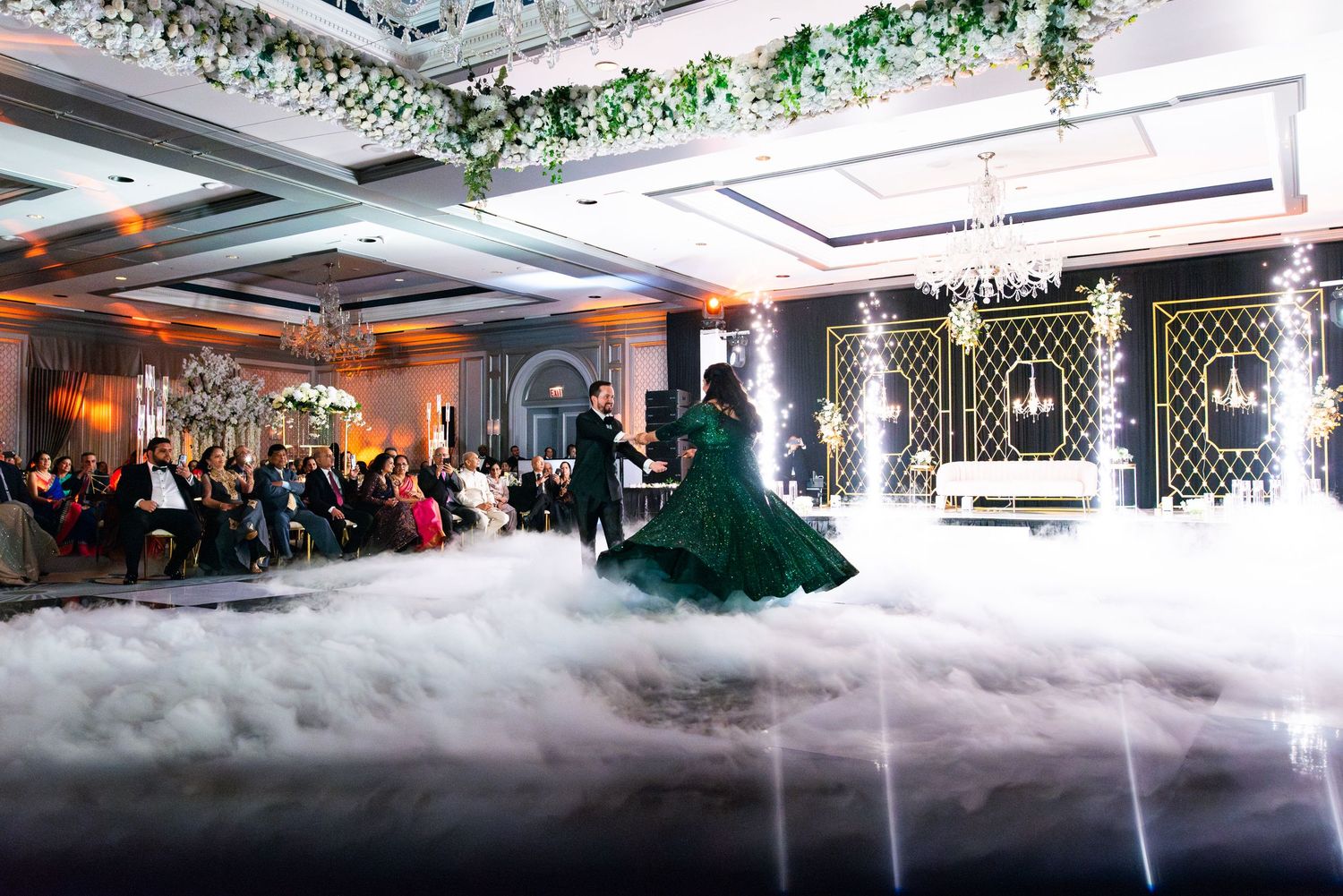 A wedding reception venue decorated with white fog effects, greenery, and ambient lighting creating a dreamy atmosphere.