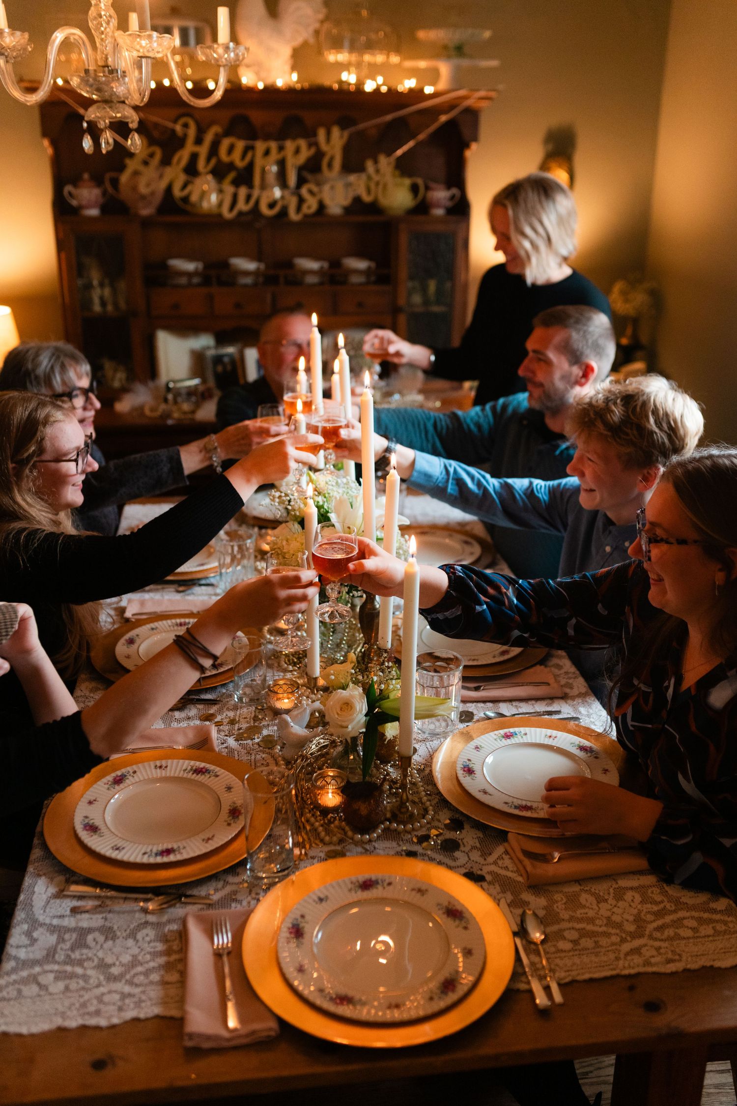 Documentary style lifestyle family session in grand rapids with people toasting their drinks at a long wooden table
