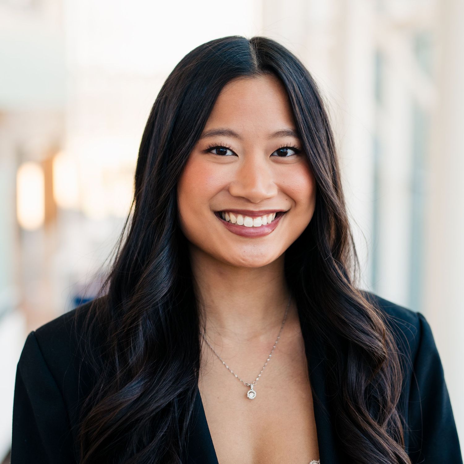 Professional headshot of GVSU student with long dark hair wearing business attire and smiling warmly against a light background.