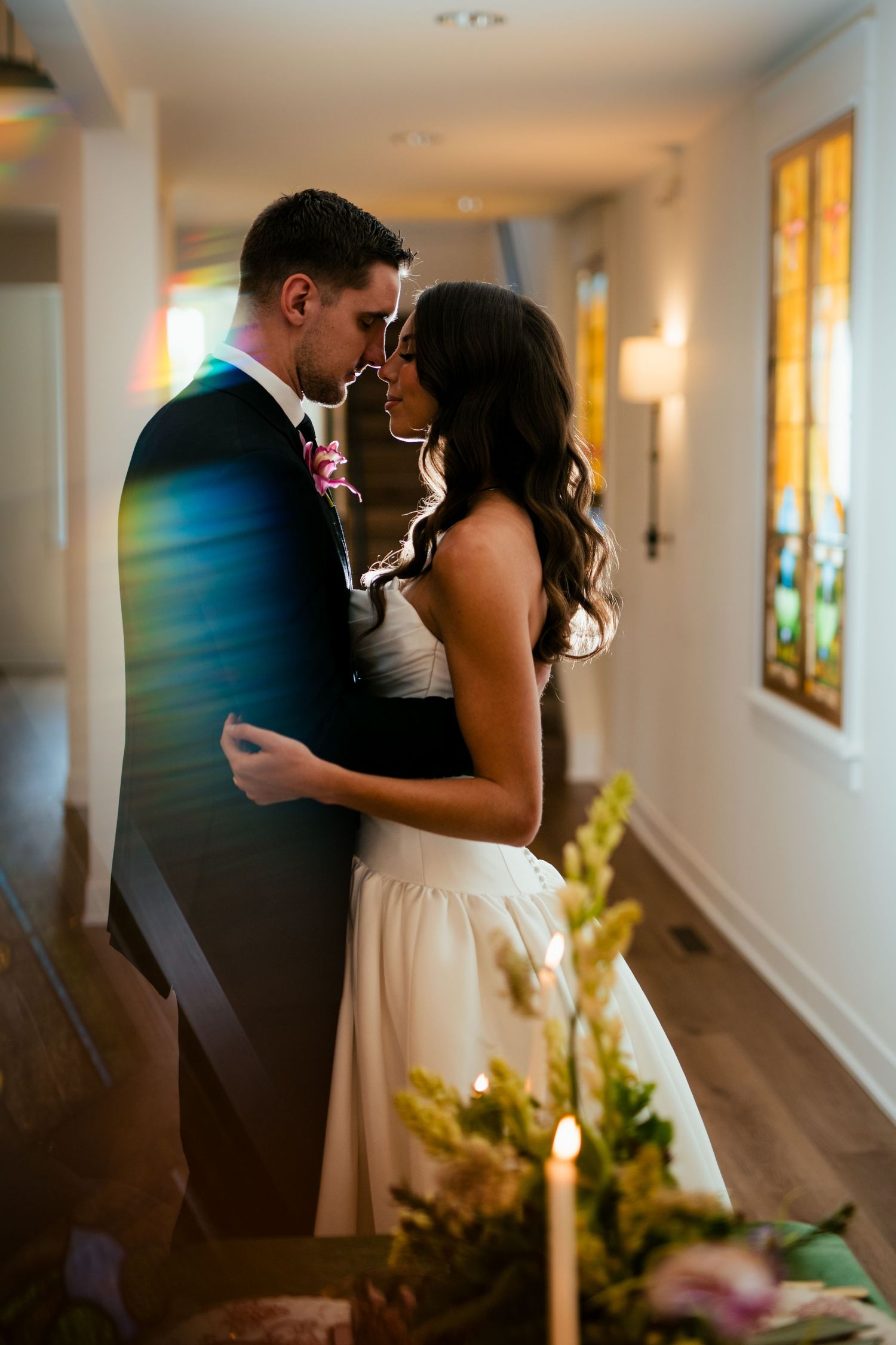 A romantic moment captured in a hallway as a couple in wedding attire shares an intimate kiss.