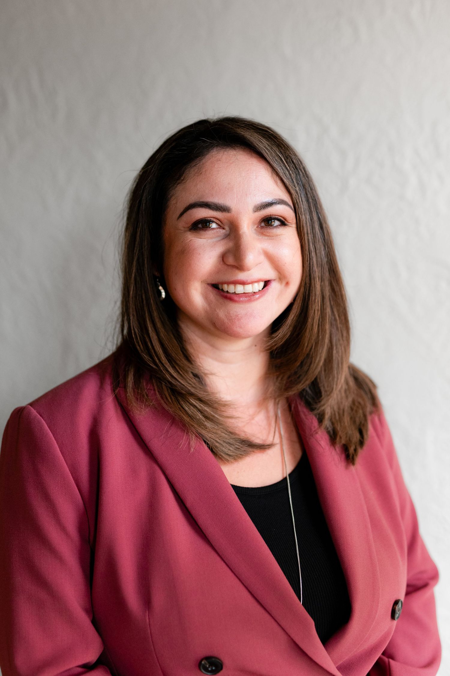 Professional headshot showing someone in a pink blazer and black top with varying expressions and poses.