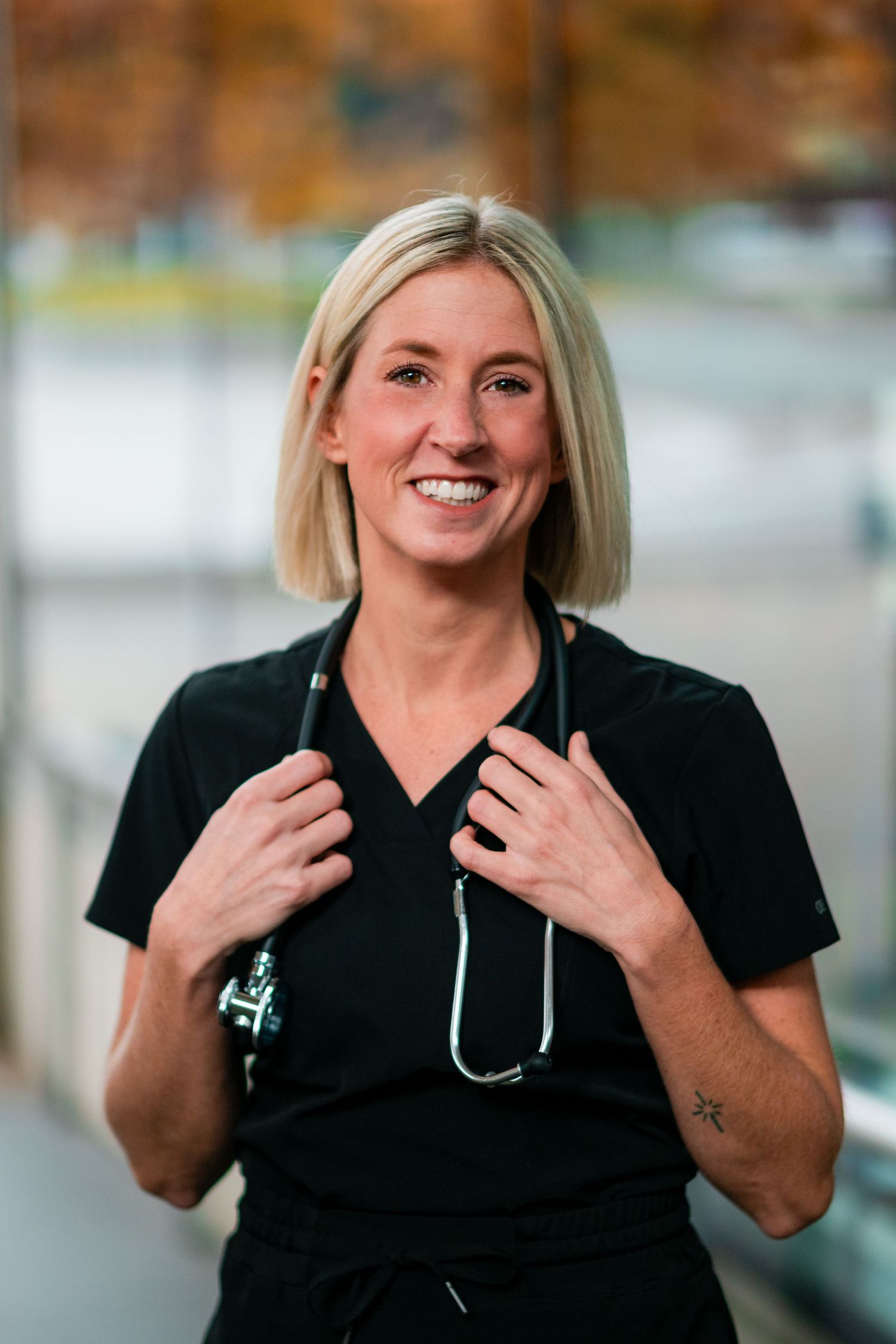 Healthcare worker in black scrubs poses for professional headshot in west michigan.