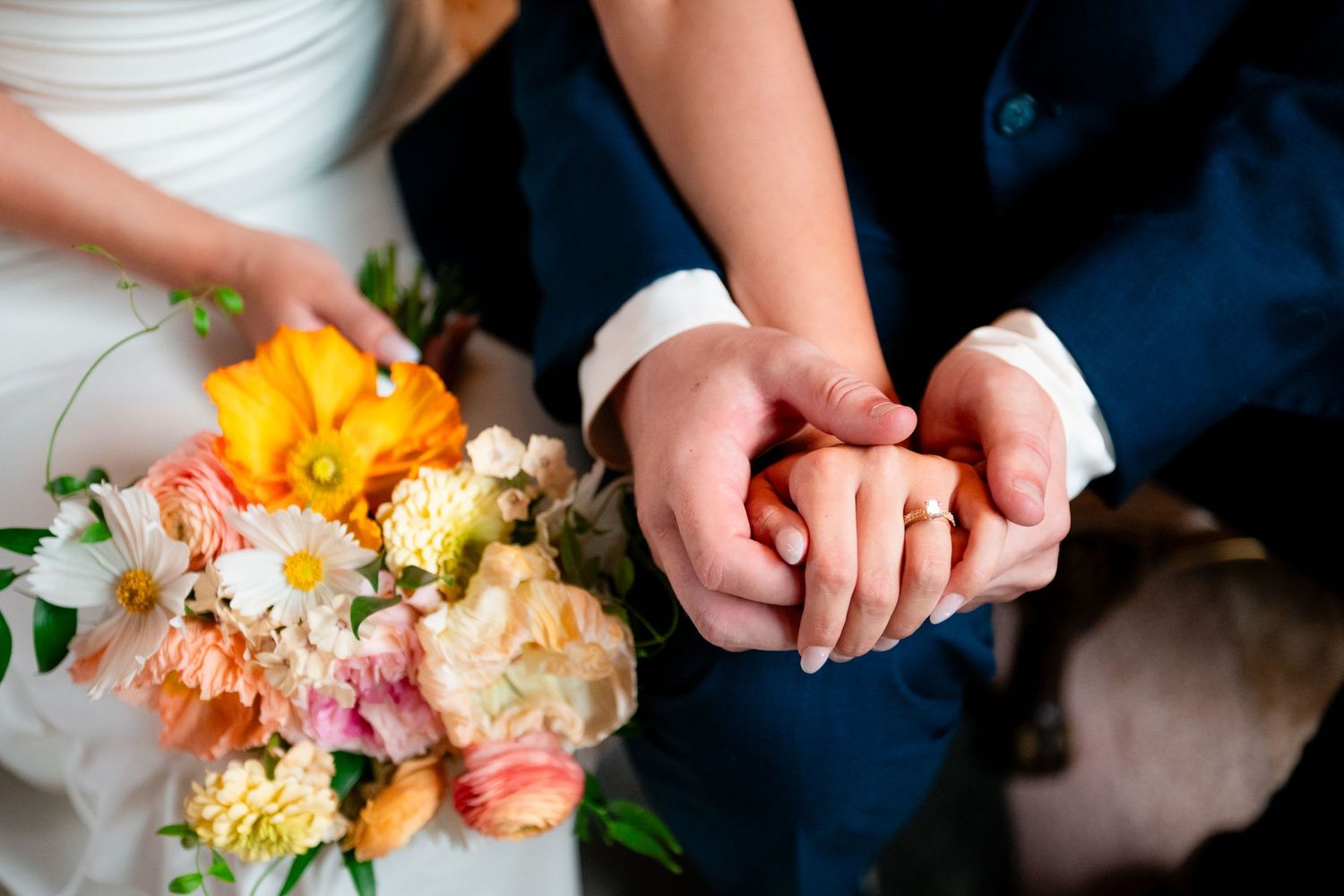 Hands arranging delicate pink, orange, and white flowers in a floral arrangement workshop setting.