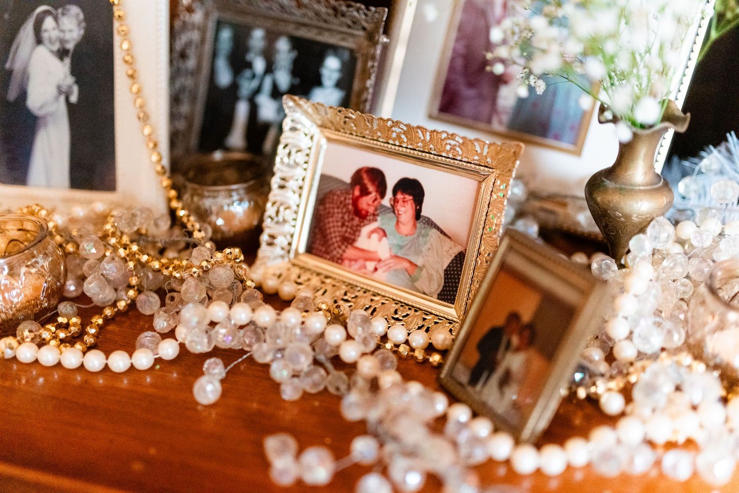 A collection of ornate gold picture frames and pearl decorations arranged on a wooden surface with soft lighting.