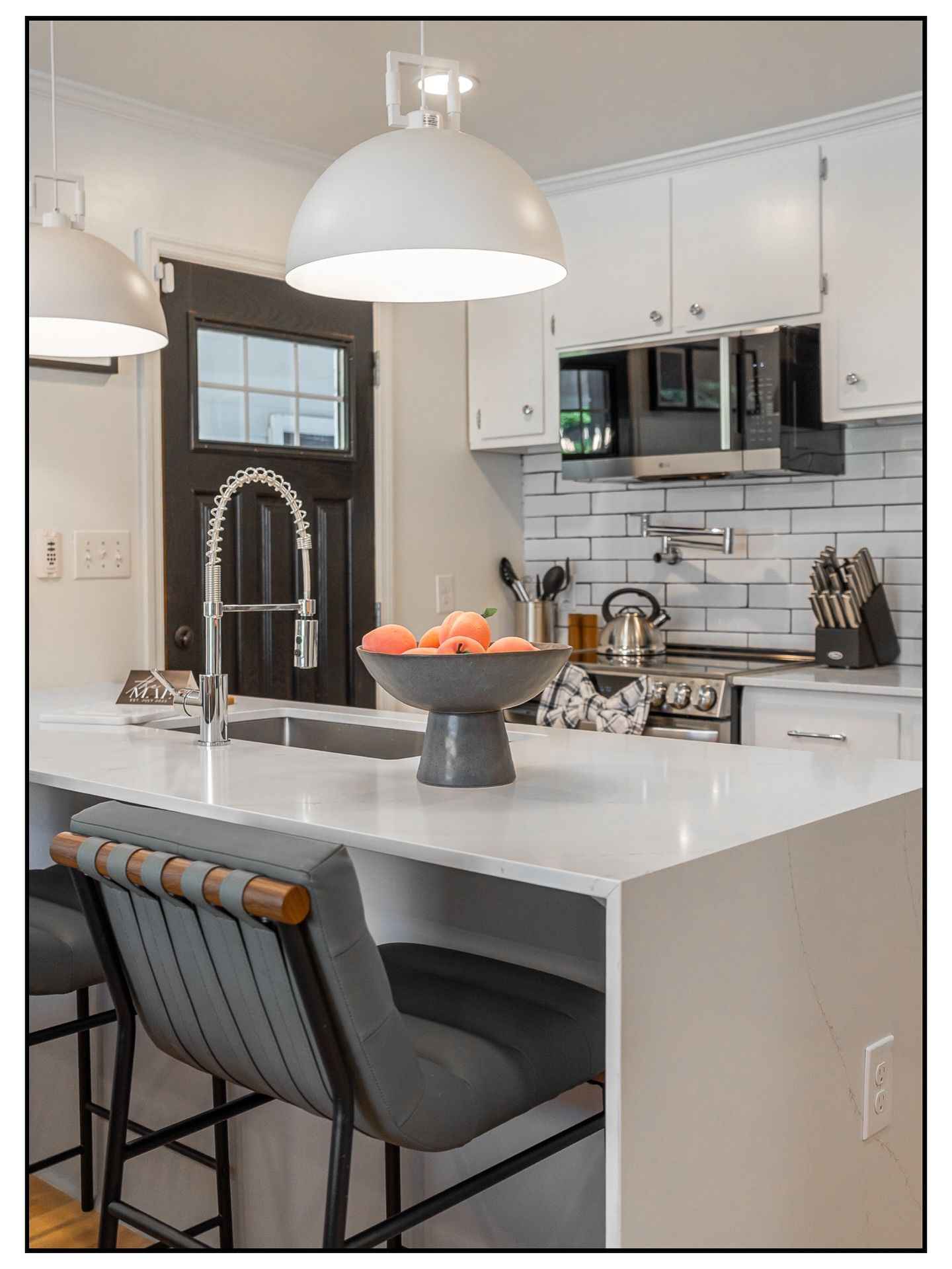Contemporary kitchen island with white countertops and gray bar stools against white tile backsplash for real estate photography in Augusta.