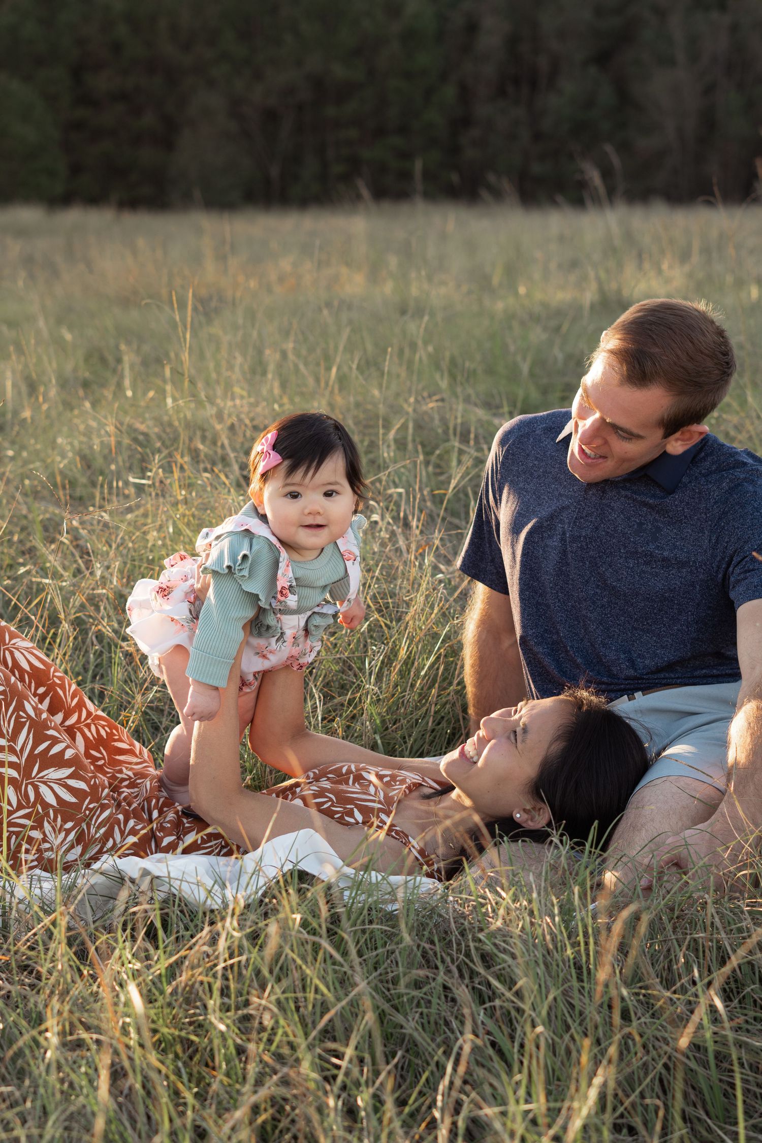 Family lying in grass field sharing playful moments during sunset in Evans, GA.