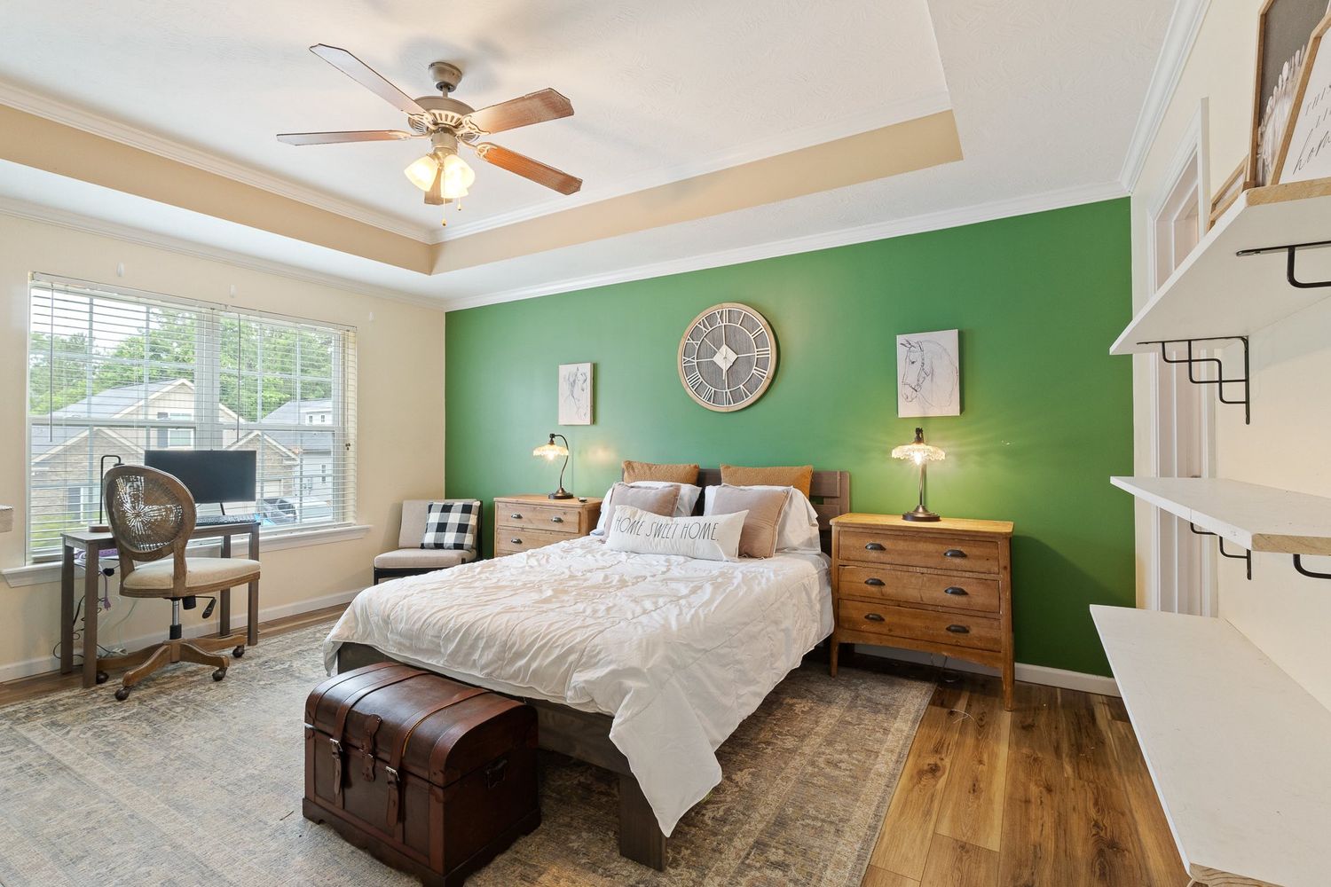 Bright bedroom with sage green accent wall and traditional wooden furniture.