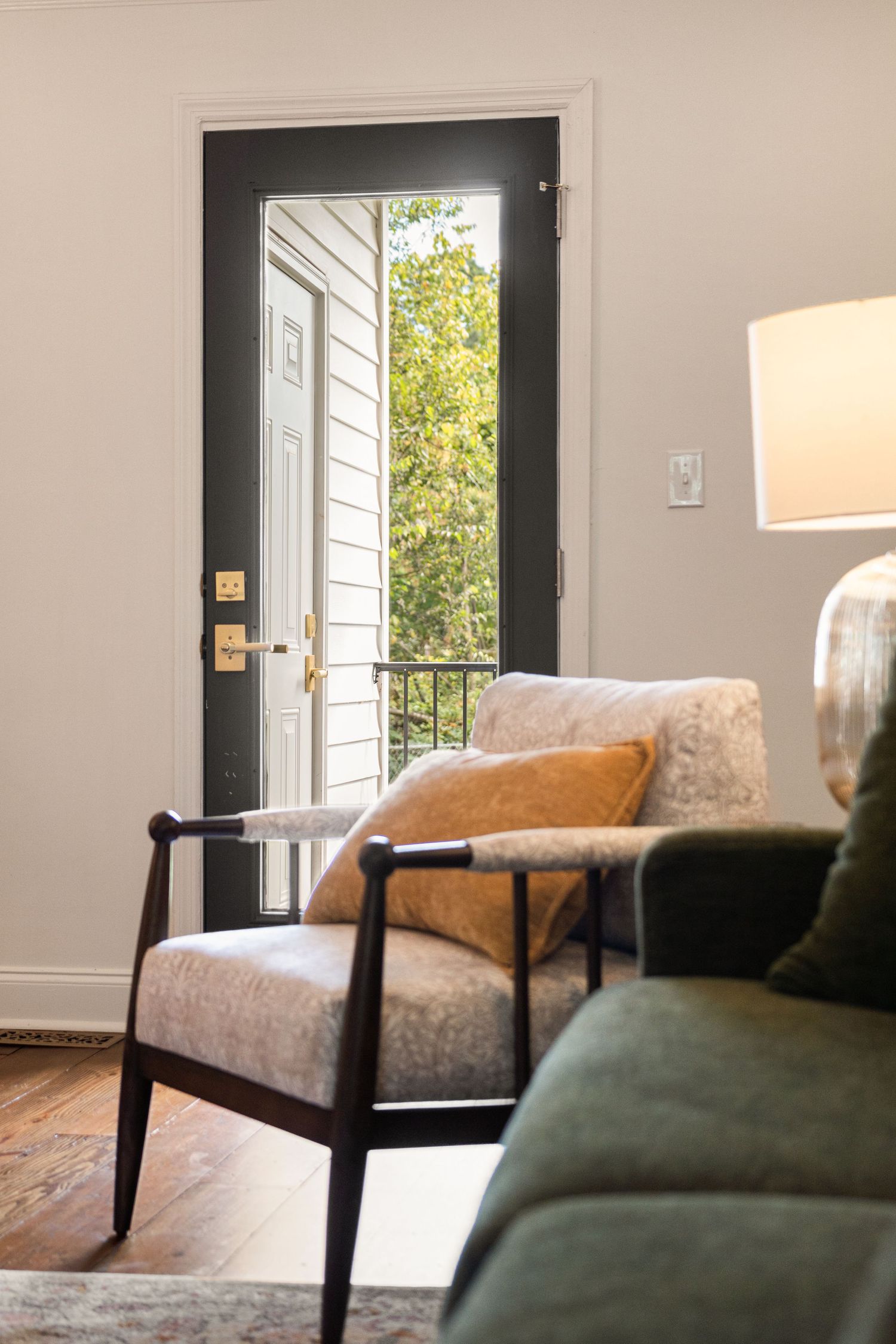 Modern seating area with green and beige upholstered chairs near black-framed glass doors for real estate photography in Augusta, GA.