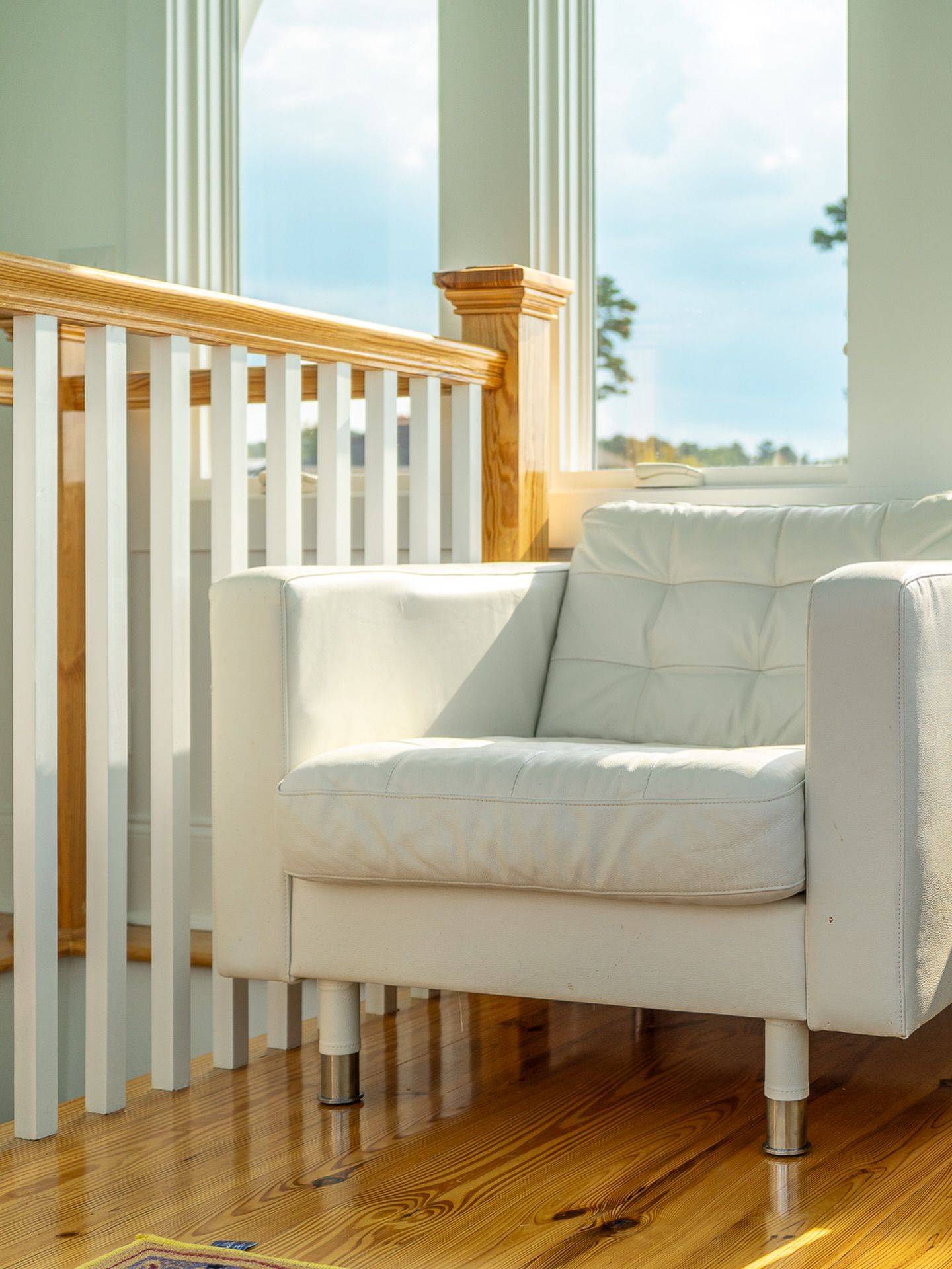 Sun-filled porch with hardwood floors and white modern furniture overlooking outdoor space for real estate photography in Augusta, GA.