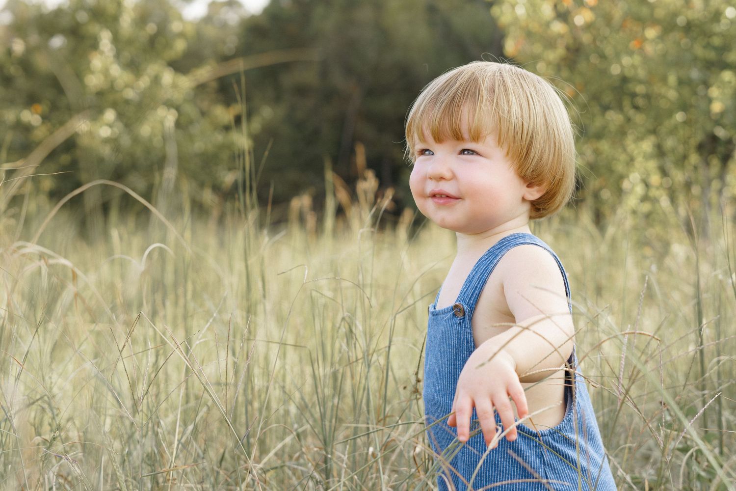 Candid family photoshoot in a natural outdoor setting with tall grass.