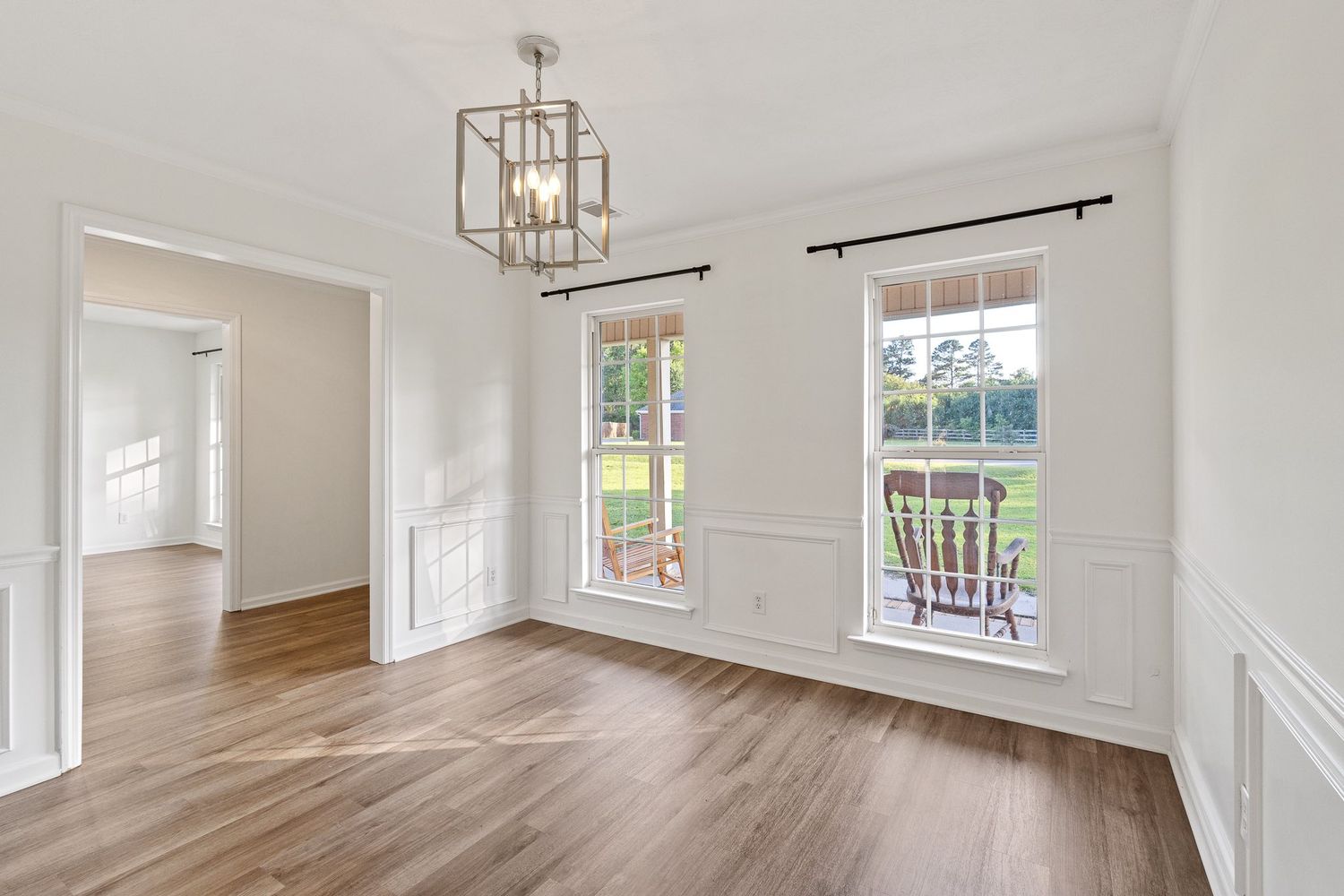Bright open concept living space with white walls, crown molding, and large windows letting in natural light for real estate photography.