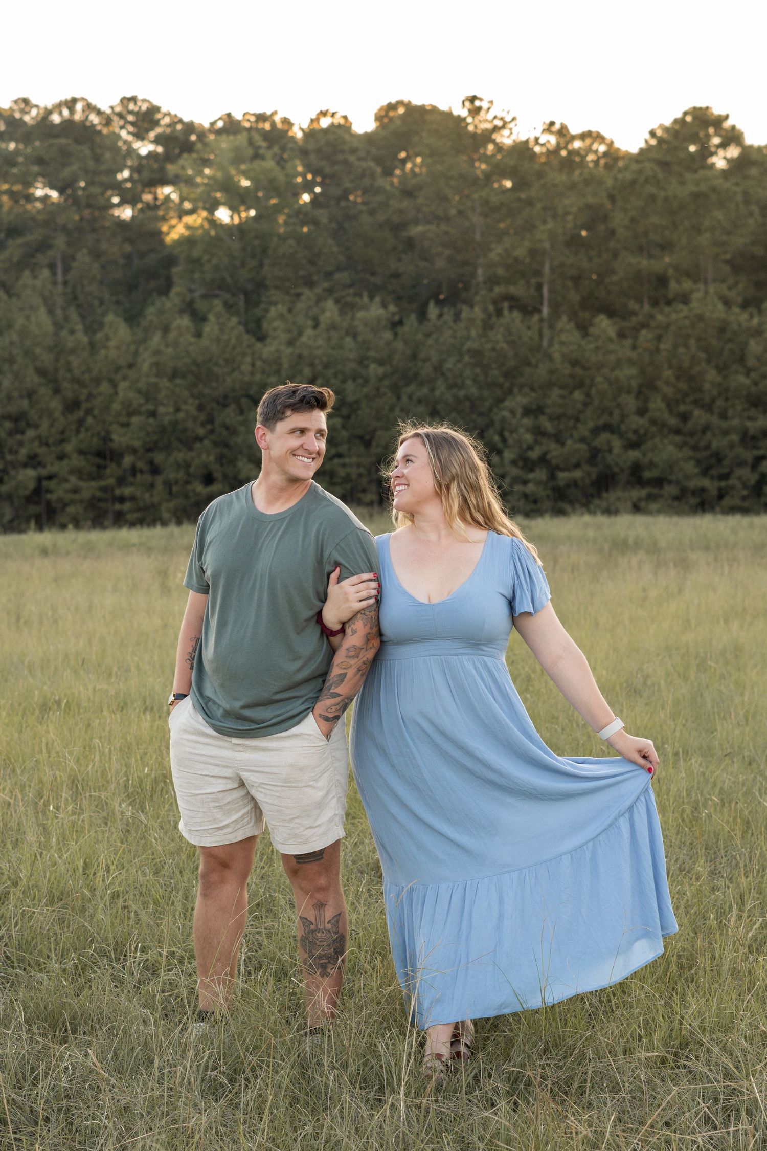 A couple poses together in a sunlit meadow during a summer evening photoshoot in Evans, GA.