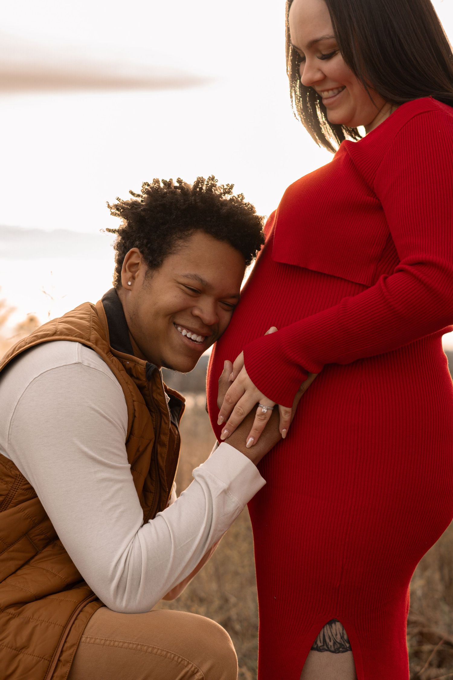 A tender moment between an expecting couple during a sunset maternity photoshoot outdoors.