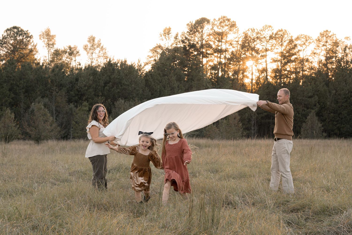 Group poses playfully in an open field during golden hour photography session in Augusta, GA.