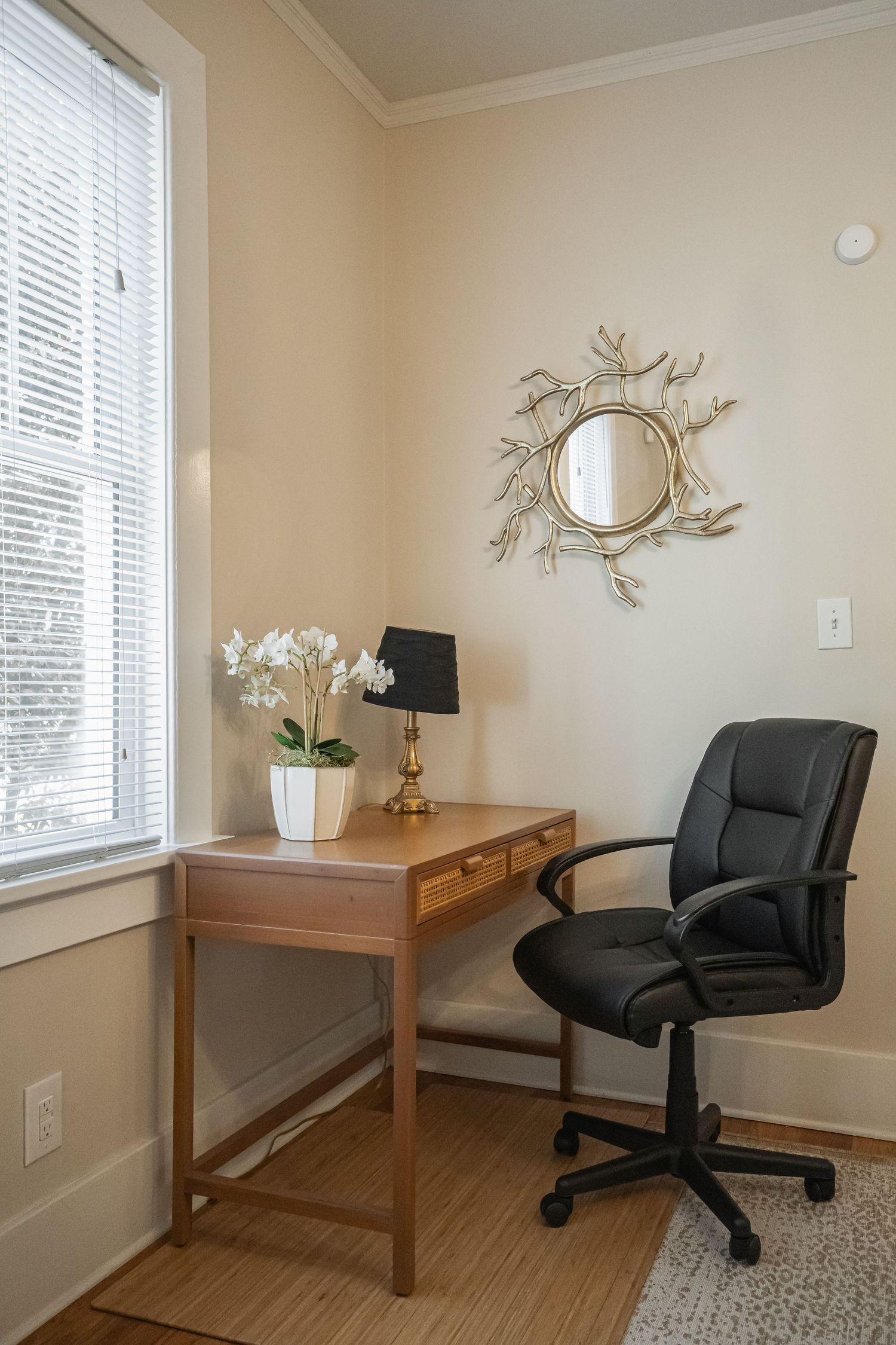 Home office space with wooden desk, black office chair, and decorative wall mirror for real estate photography in Augusta, GA.