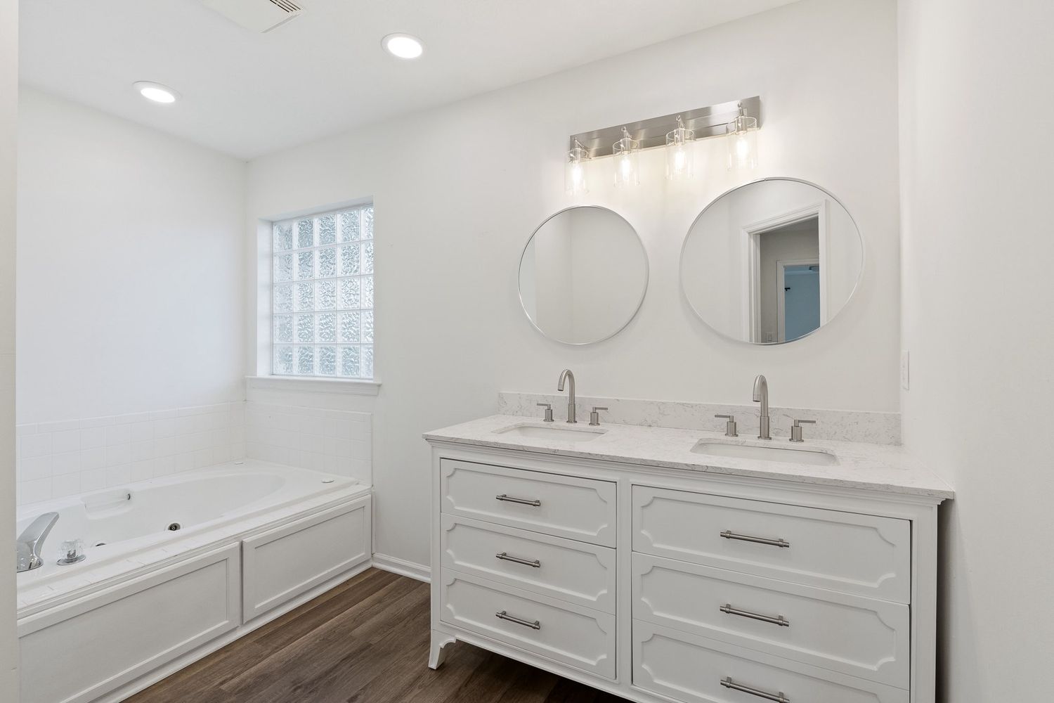 Sleek bathroom with double vanity, white cabinets, and modern fixtures for real estate photography in Augusta, GA