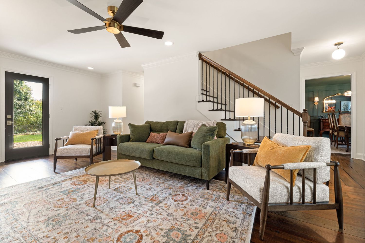 Open concept living space with modern furniture, hardwood floors, and staircase railing detail.