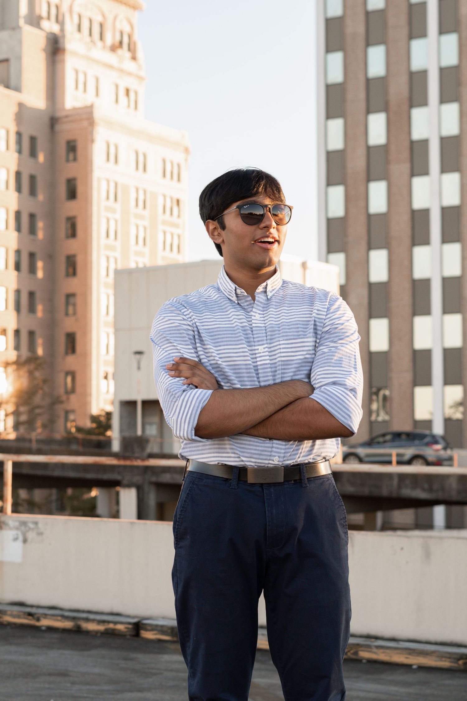 Urban portrait against brick building wearing striped shirt and dark pants for photography in Augusta, GA.
