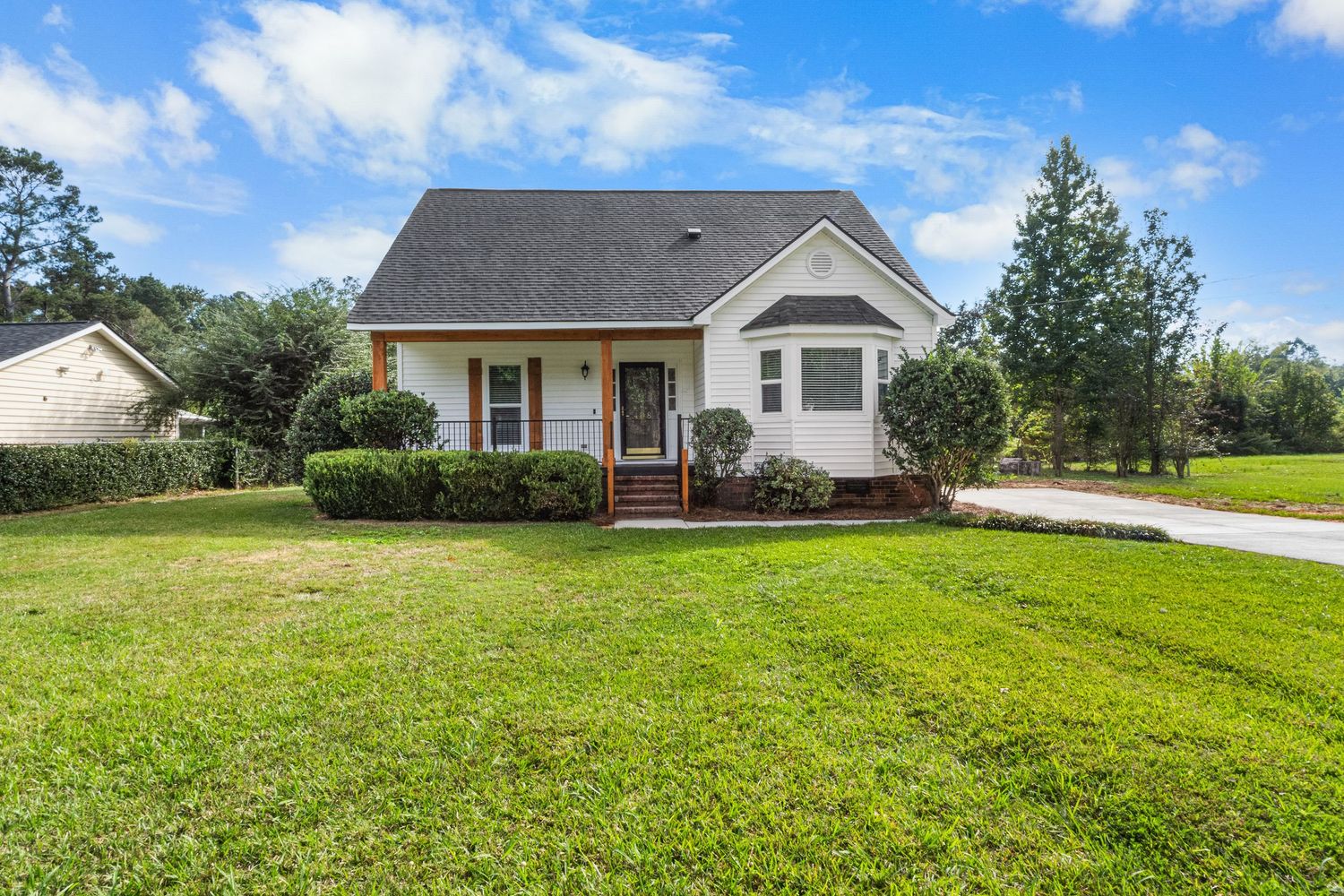 Panoramic view of a suburban house with well-maintained green lawn under blue skies for real estate photography in Augusta, GA.