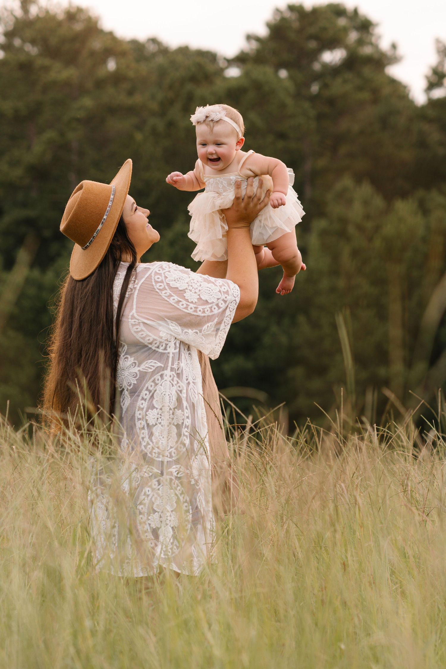 Playful moments captured in a field with tall grass and white lace dress at sunset.