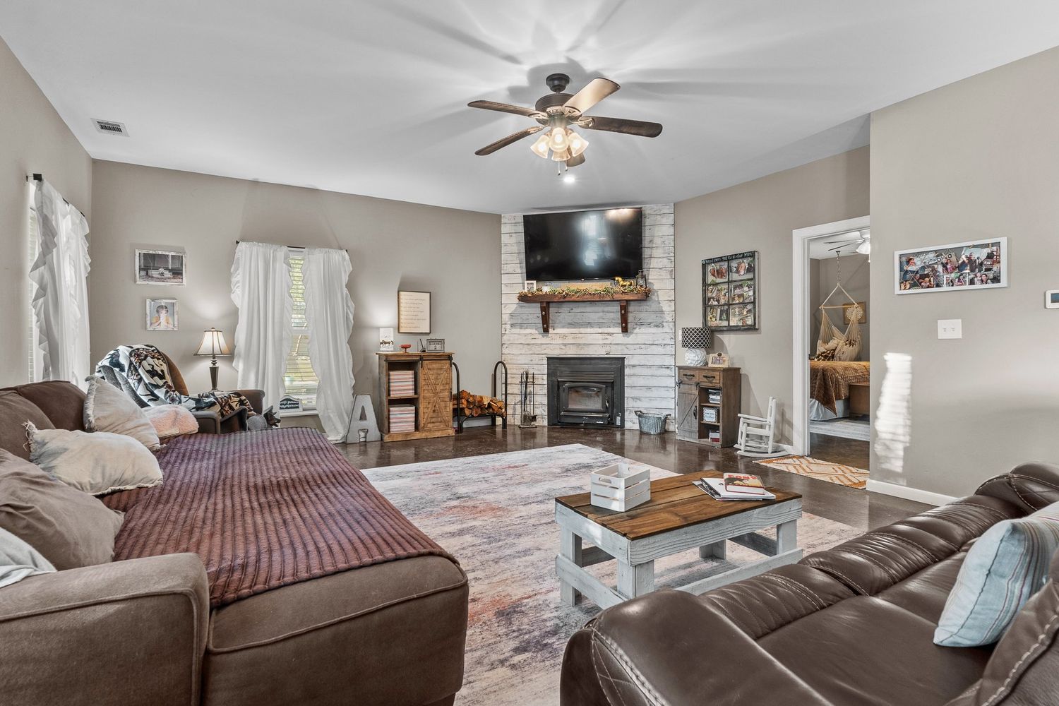 Cozy living room with sectional sofa, wall-mounted TV, and decorative wall art for real estate photography in Augusta, GA.
