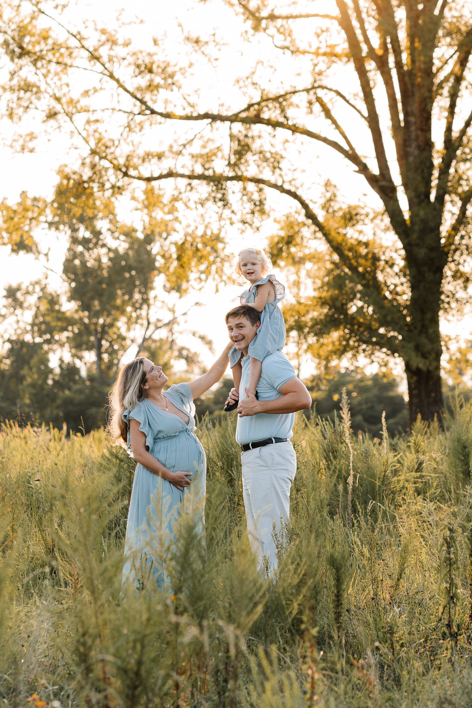Romantic couple dancing in tall grass during golden hour with trees behind them for portrait photography in Augusta, GA.