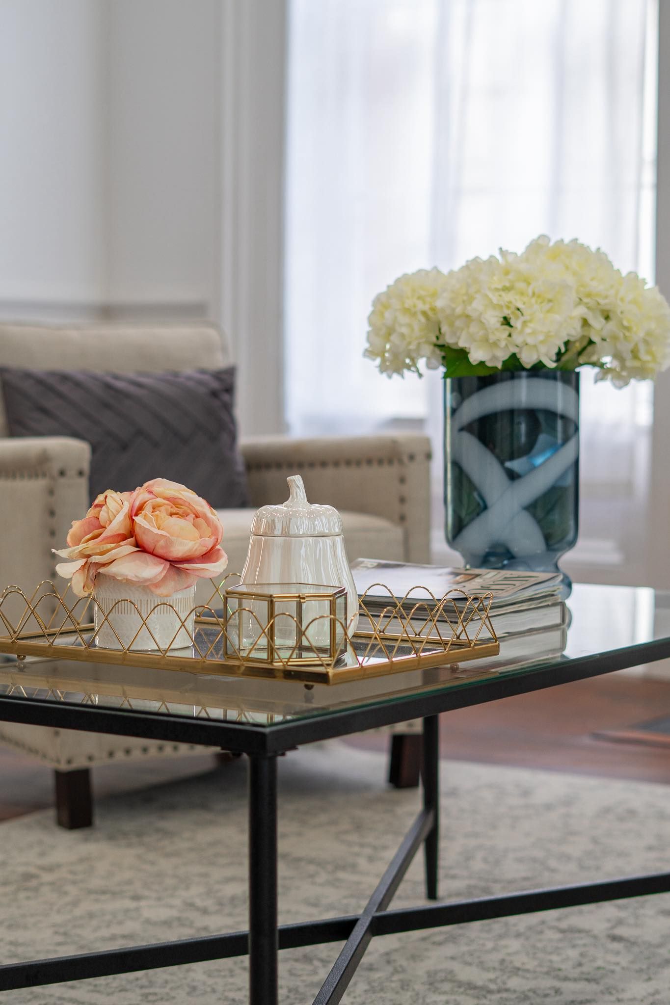 Modern coffee table decorated with flowers and geometric gold accessories.