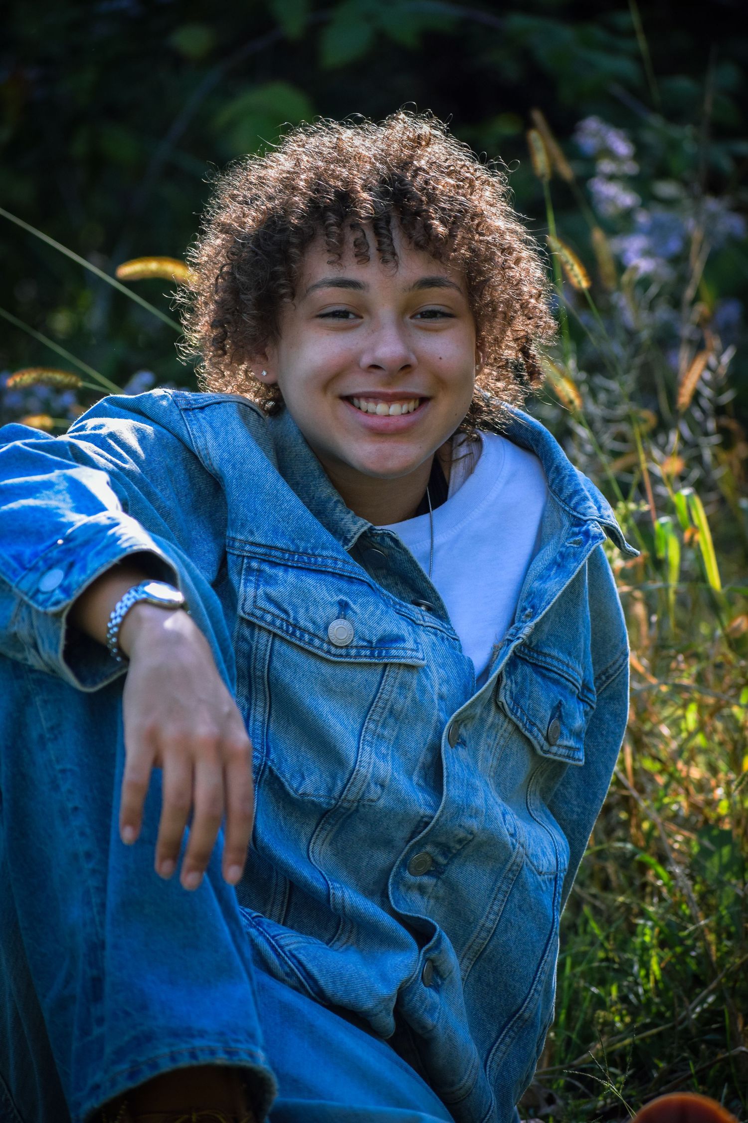 Relaxed outdoor portrait featuring denim and white clothing among wildflowers.