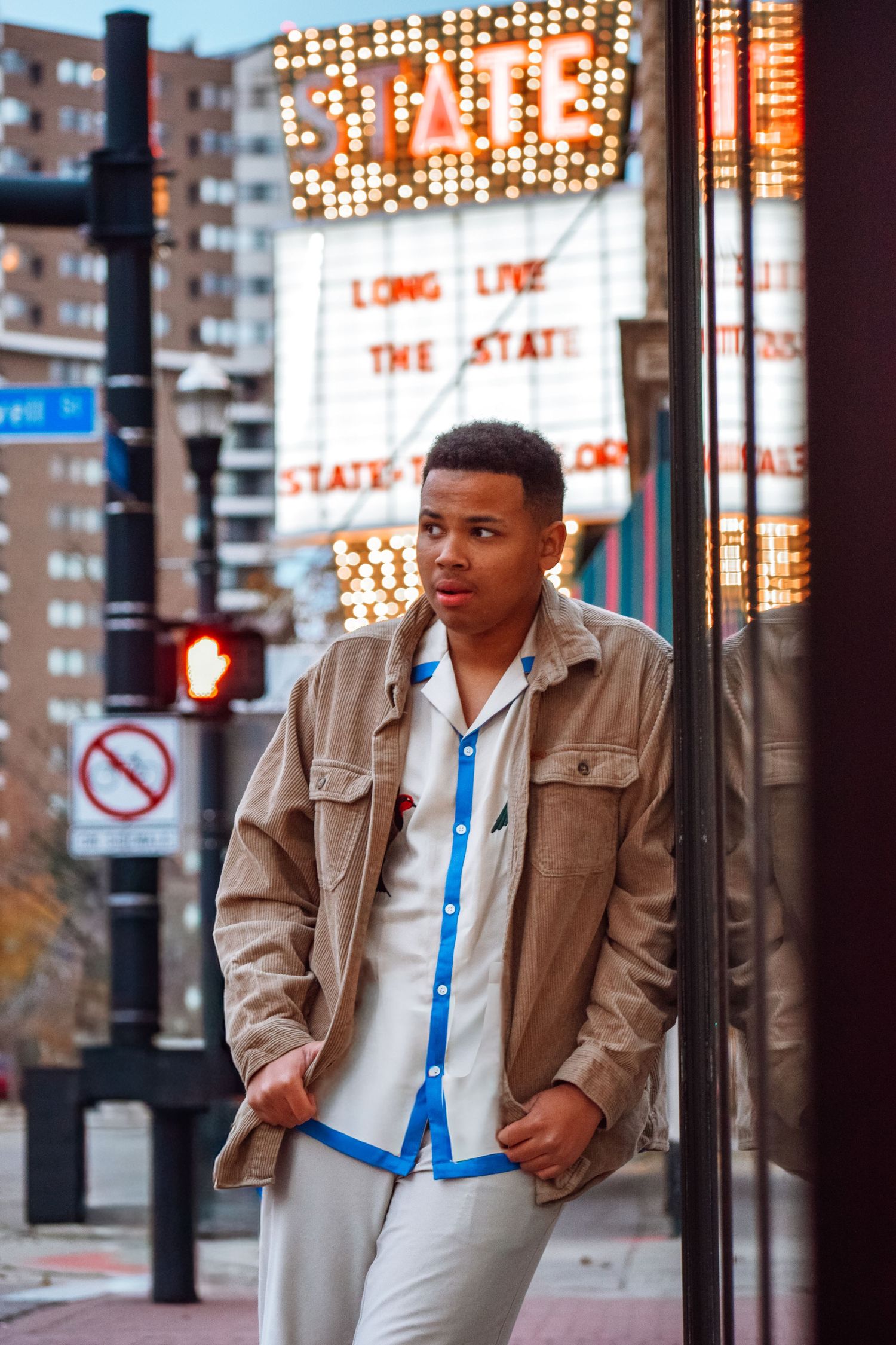 Street style portrait with illuminated vintage theater marquee and urban architecture.