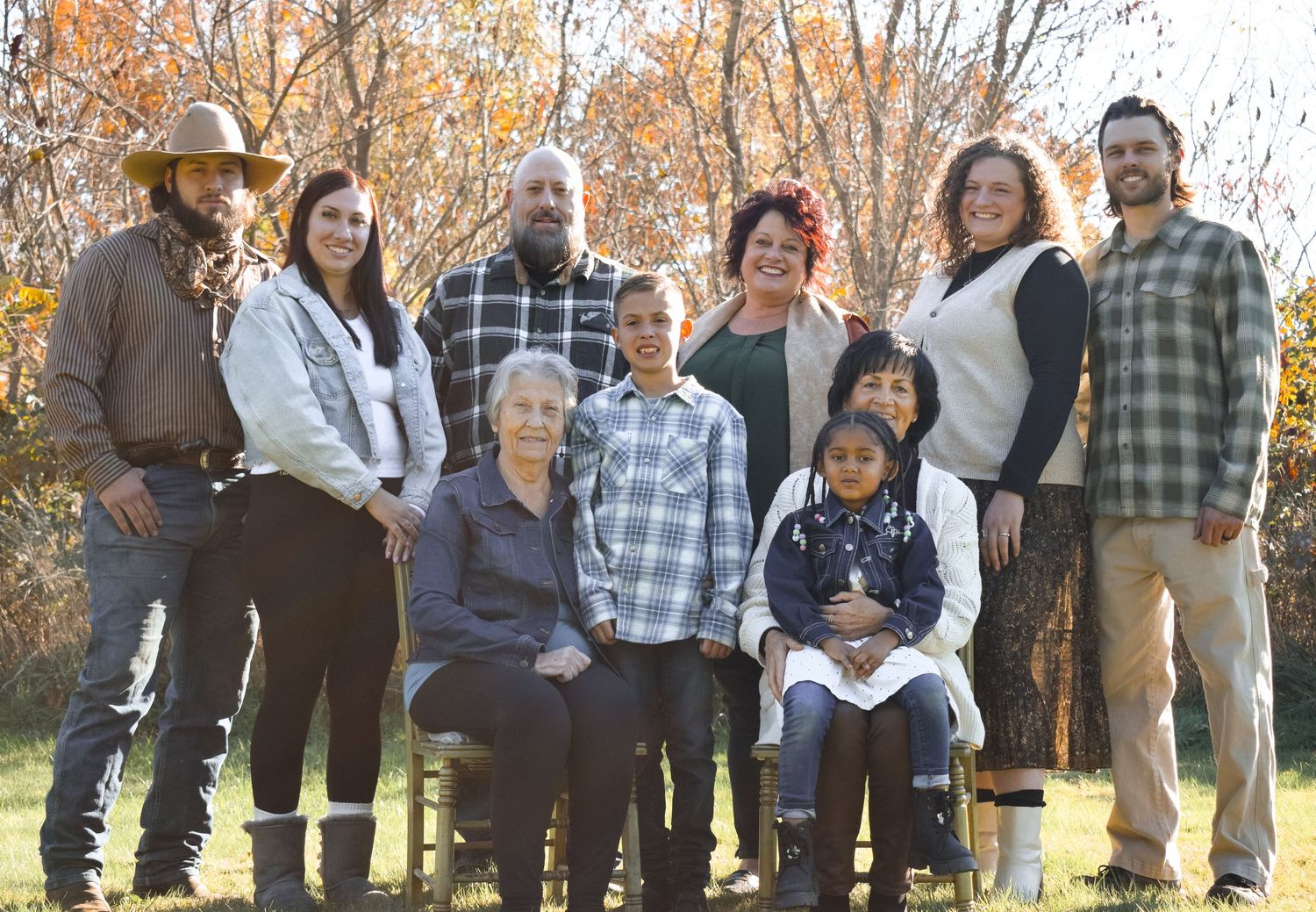 Group photo taken outdoors with autumn trees showing golden foliage in the background.