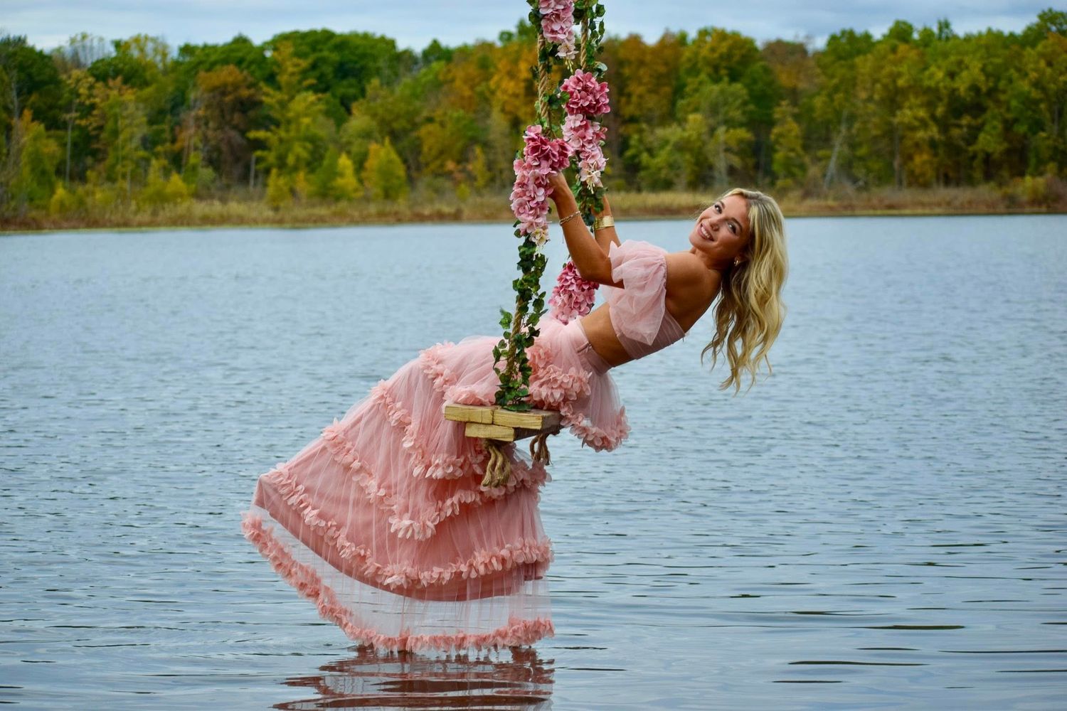 Romantic scene of pink dress flowing in lake water surrounded by lush greenery.
