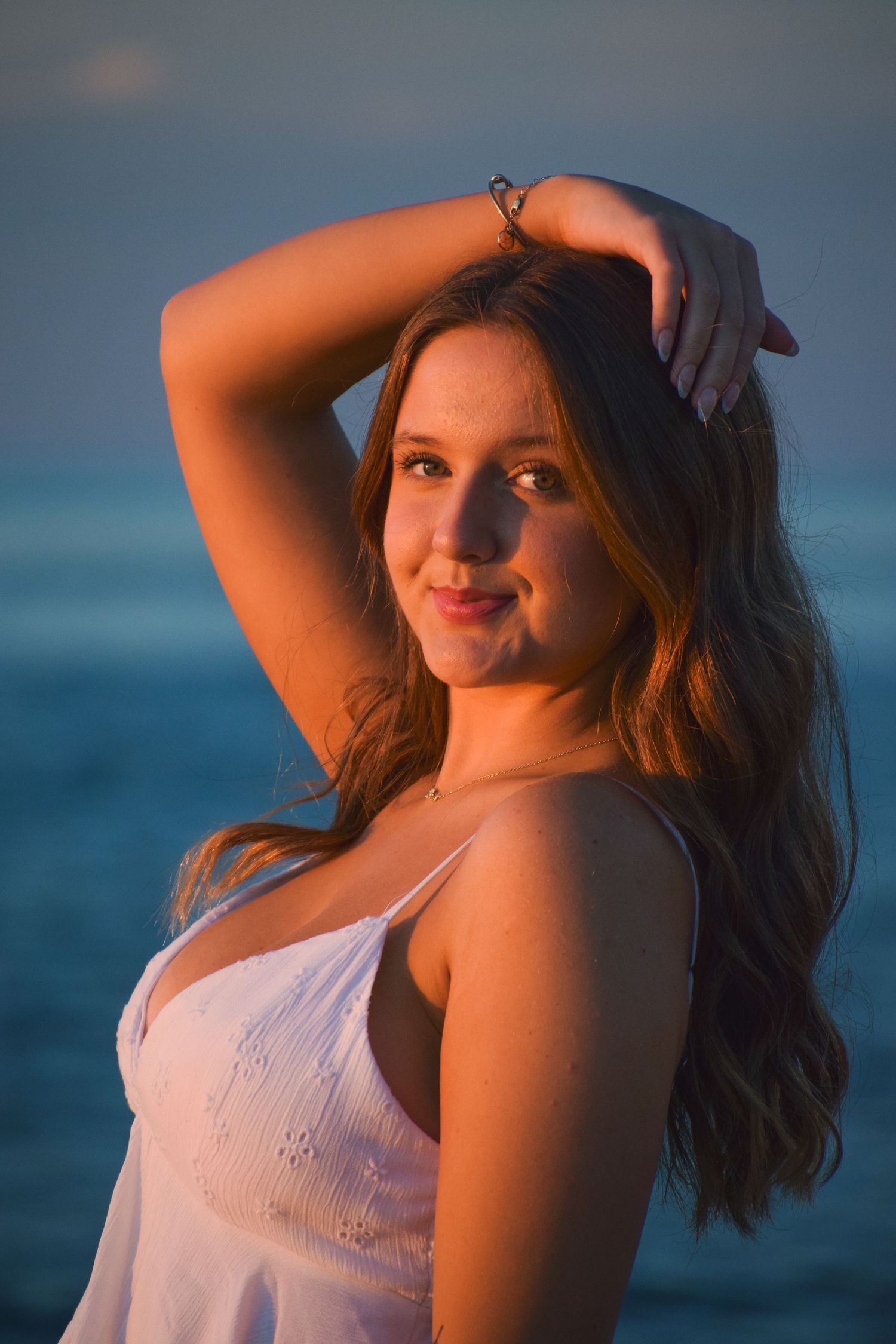 Sunset beach portrait with warm golden lighting and ocean backdrop.