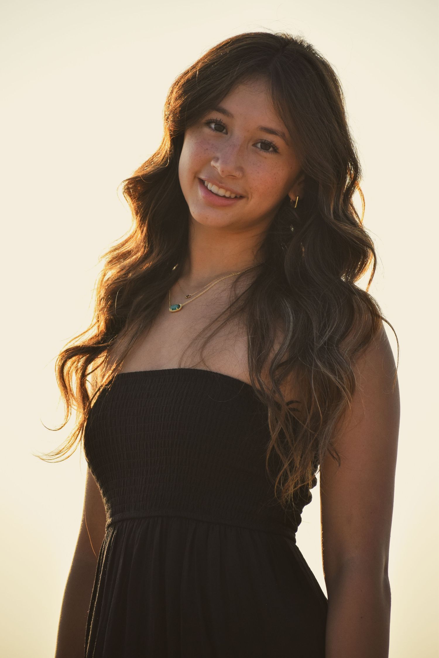 Backlit portrait series showing woman in black dress with flowing hair against bright background.