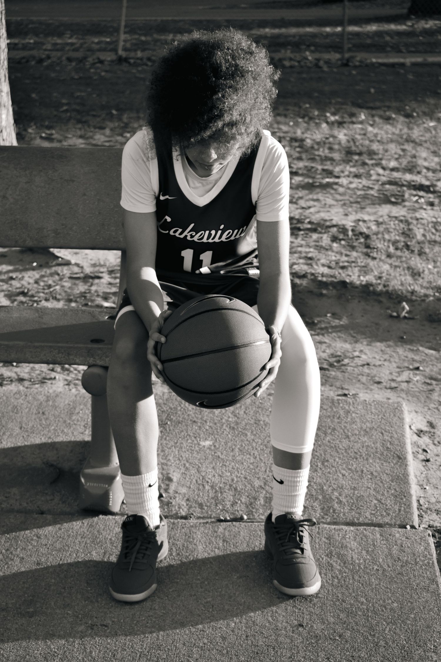Black and white photo showing basketball player's stance on concrete court.