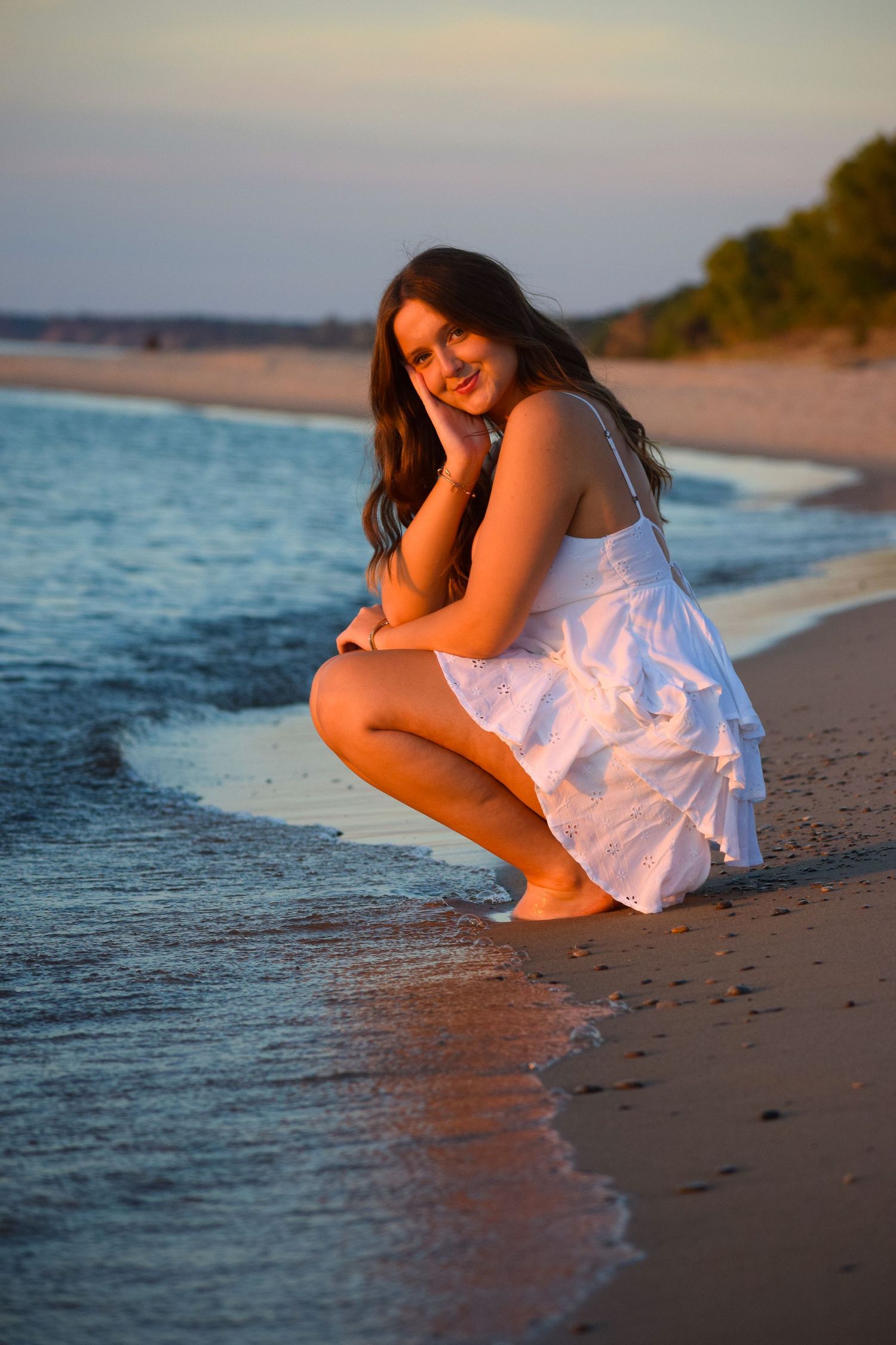 White dress photoshoot at beach shoreline during golden hour.