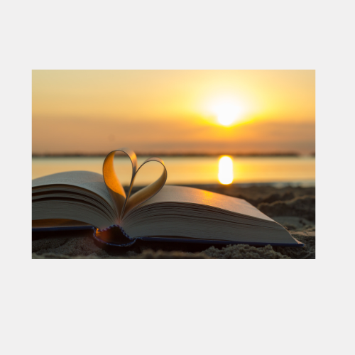 Open book with heart-shaped pages silhouetted against a golden sunset over the ocean.