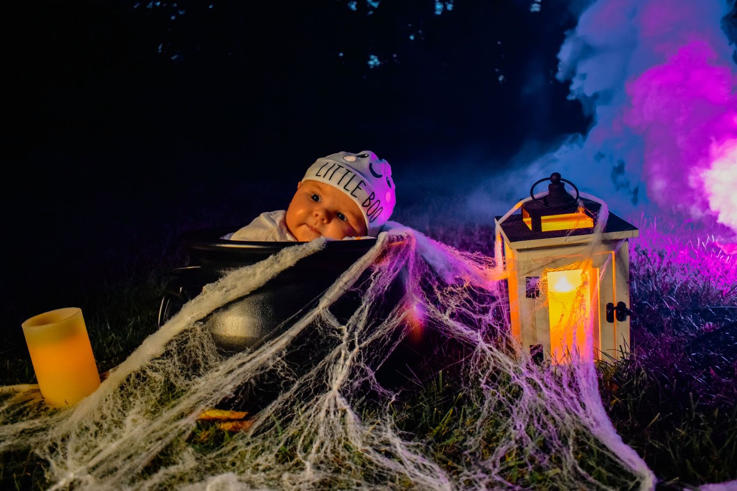 Halloween decoration with spooky lantern and cobwebs illuminated by purple lighting at night.