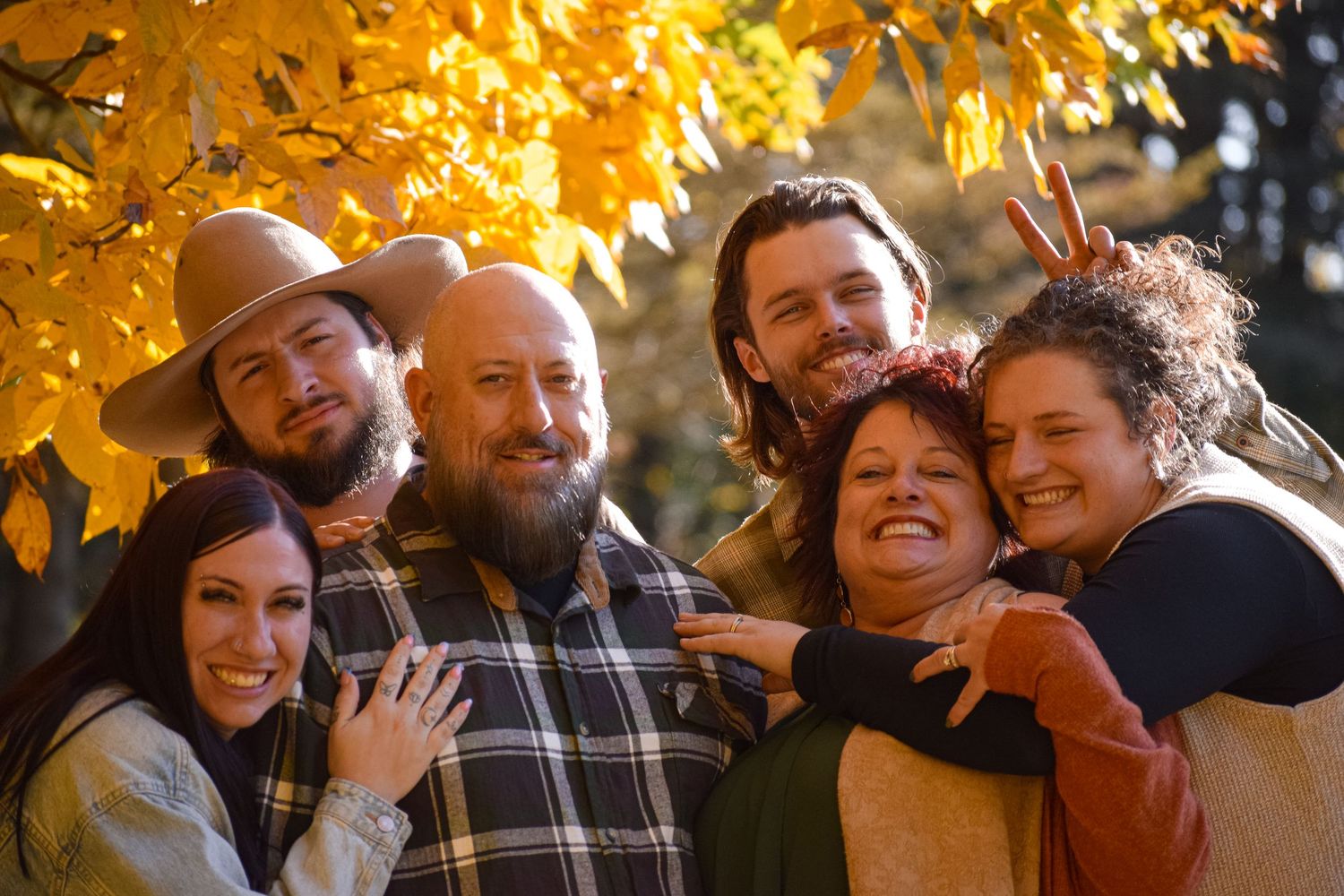 Candid group shot with people laughing together under bright yellow fall foliage.