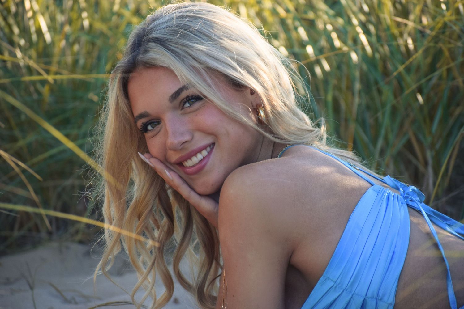 Outdoor photoshoot in a field of tall grass featuring someone in a blue sundress.