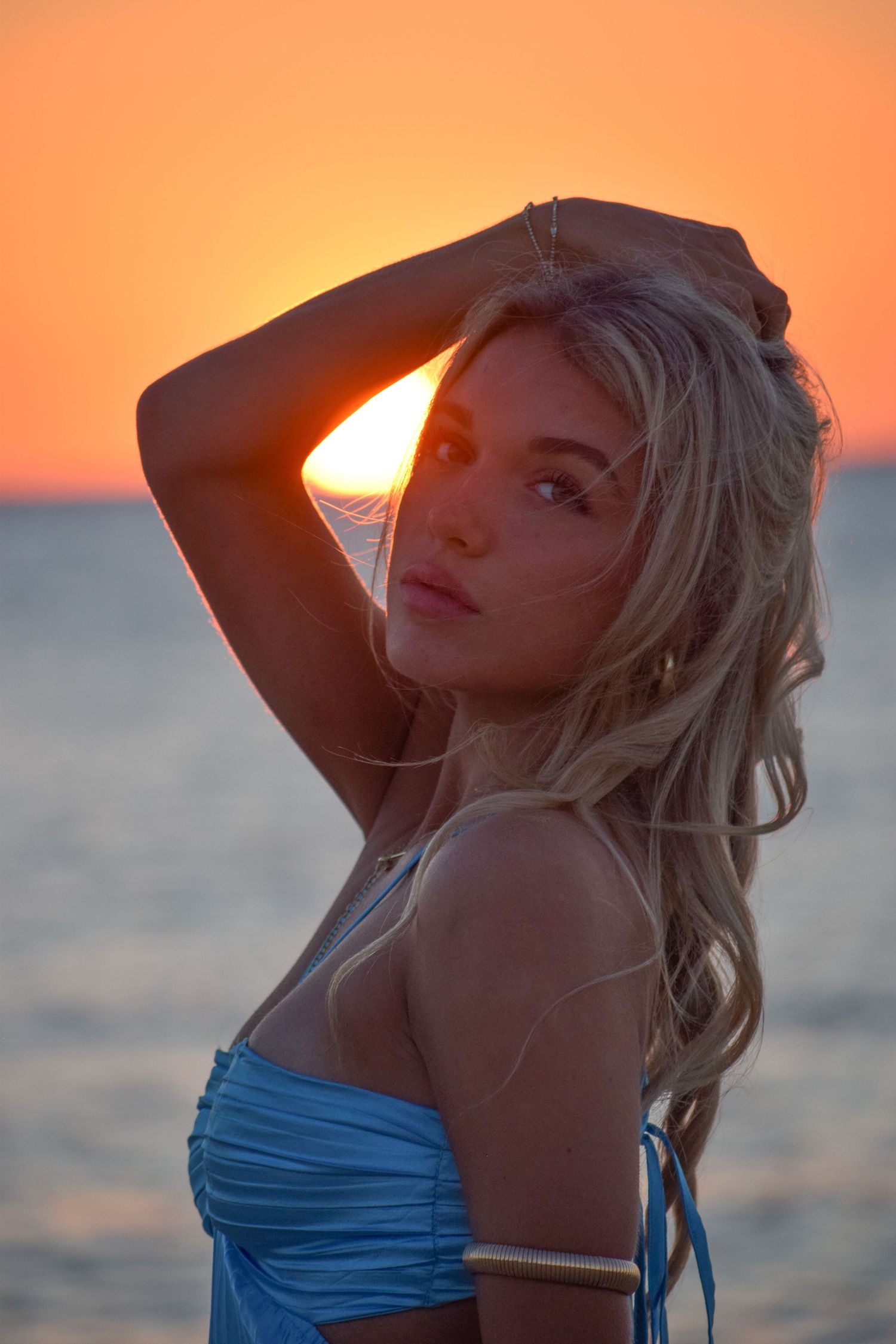 Sunset beach portraits with orange sky and someone wearing a blue top.