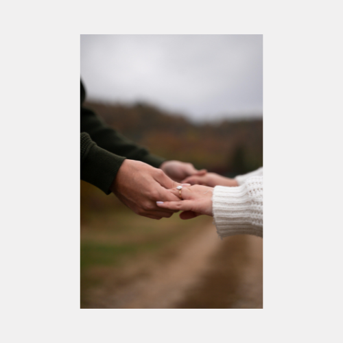 Two hands reaching towards each other in a tender moment against a blurred natural background.