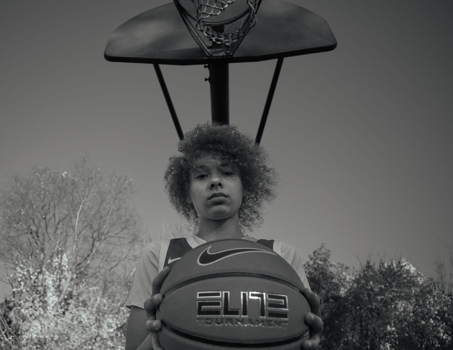 Low-angle view of basketball hoop and backboard against cloudy sky.