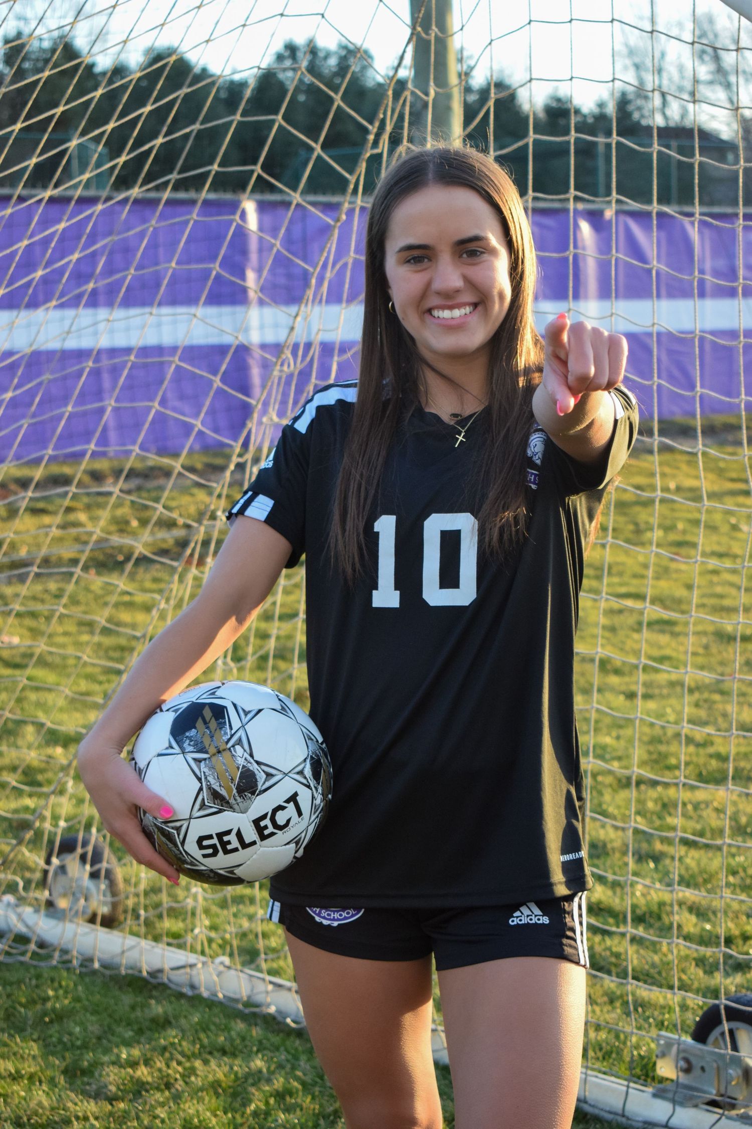 Soccer players in black jerseys posing with Select balls by goal net.