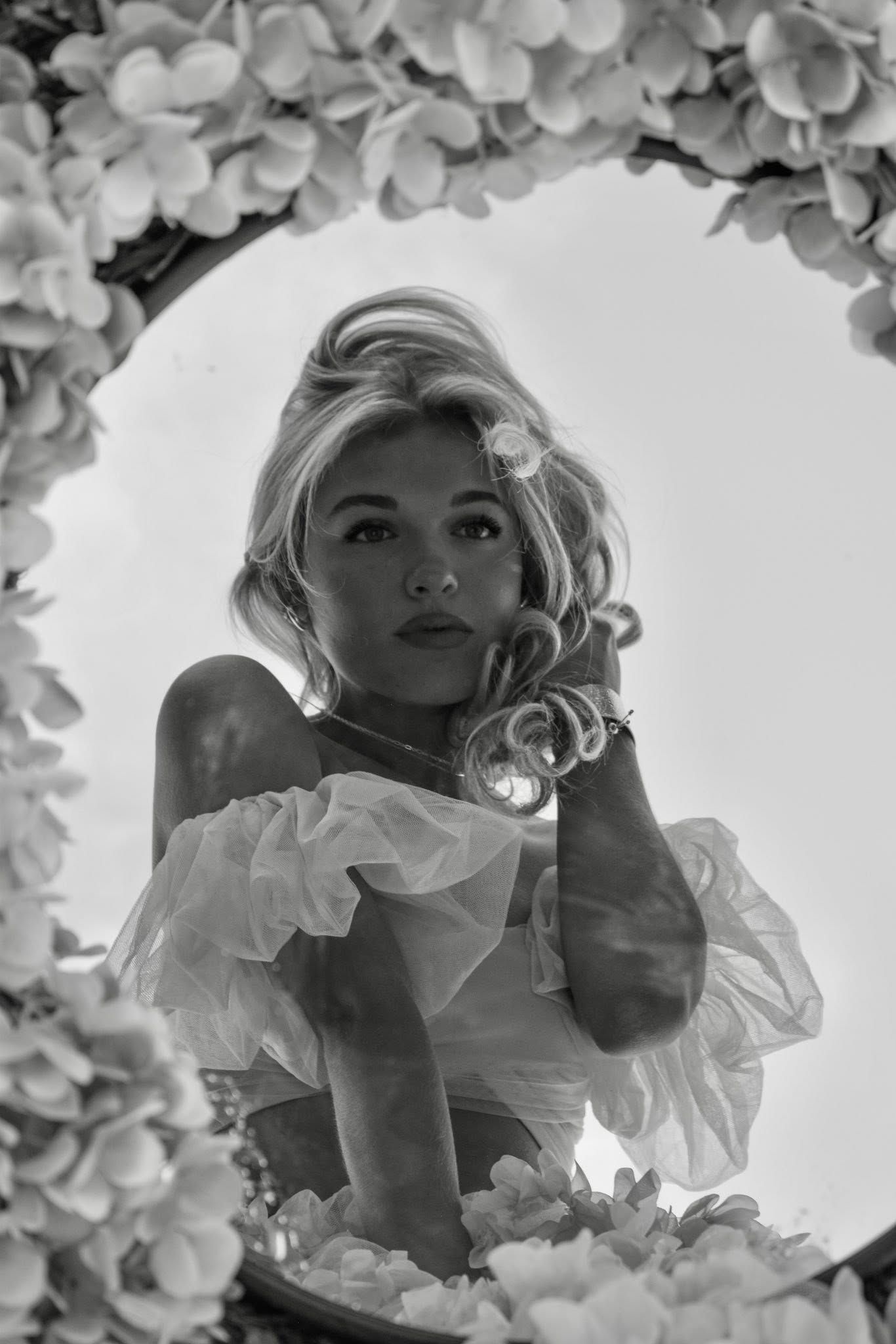 Ethereal black and white portrait through floral frame creating dreamy vintage aesthetic.