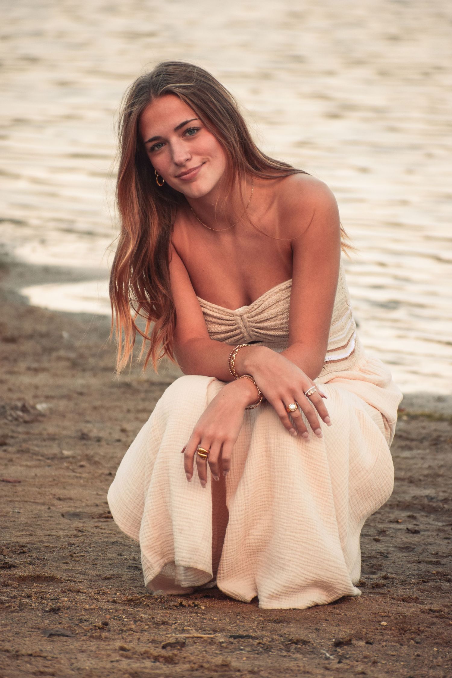 Romantic beach photoshoot at sunset featuring soft peachy tones and flowing fabric.