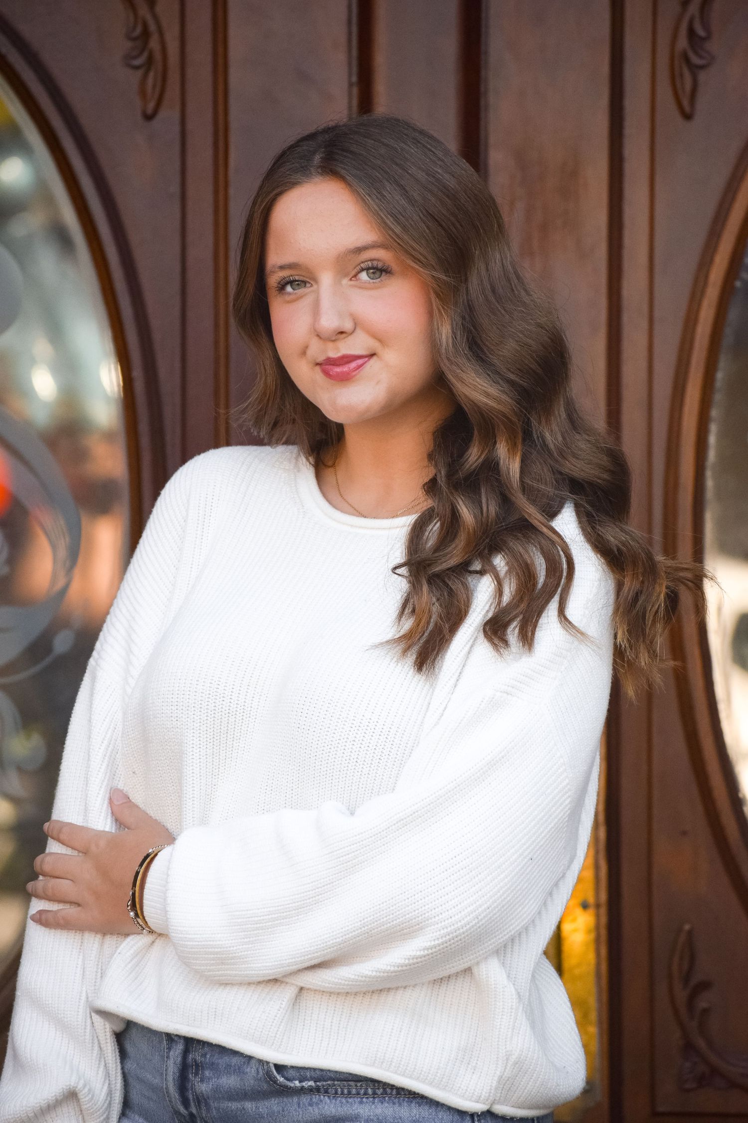 Cozy white knit sweater fashion photos against wooden door backdrop.